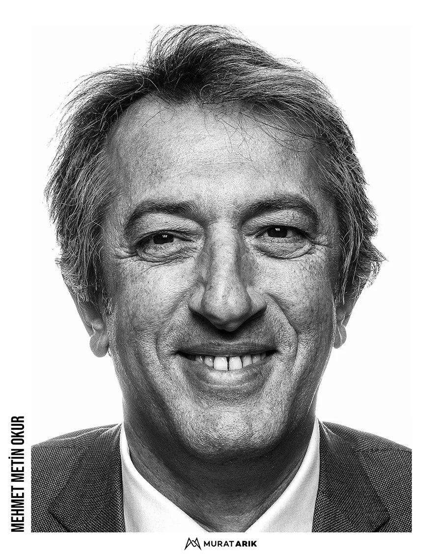 Black and white photograph of a smiling middle-aged man with gray hair, wearing a suit and tie.