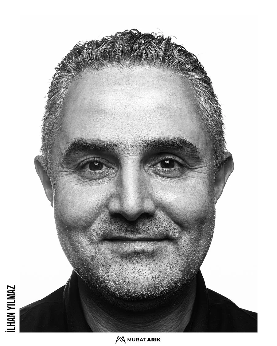Black and white close-up portrait of a middle-aged man with short, wavy hair, smiling slightly, wearing a collared shirt.