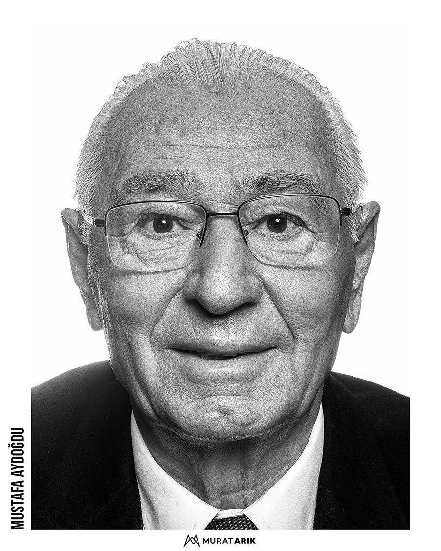 Black and white portrait of an elderly man with glasses, wearing a suit and tie, smiling slightly.