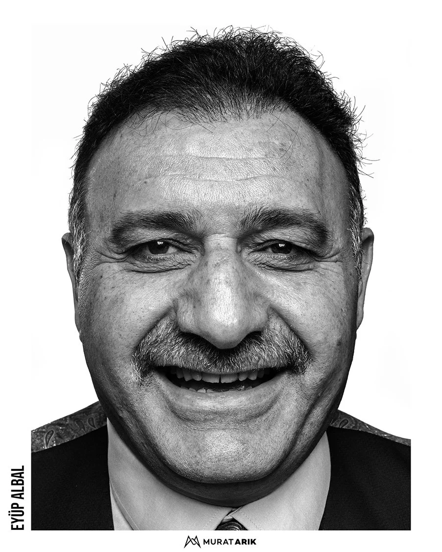 Black and white close-up portrait of a middle-aged man with dark hair, a mustache, and a bright smile.