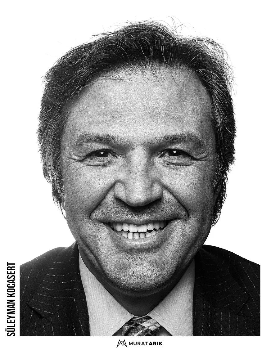 Black and white portrait of a smiling man with gray hair, wearing a suit and tie.
