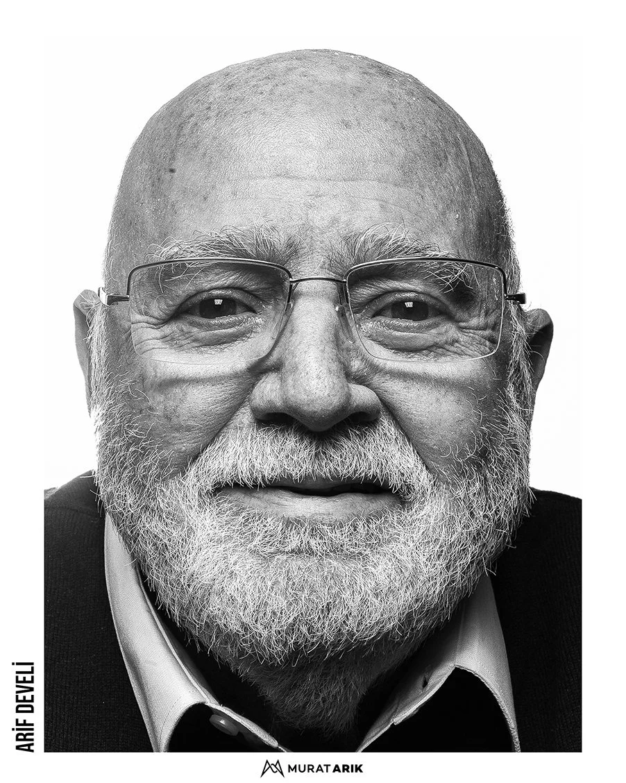 Black-and-white portrait of an older man with glasses, a beard, and a bald head, smiling softly.