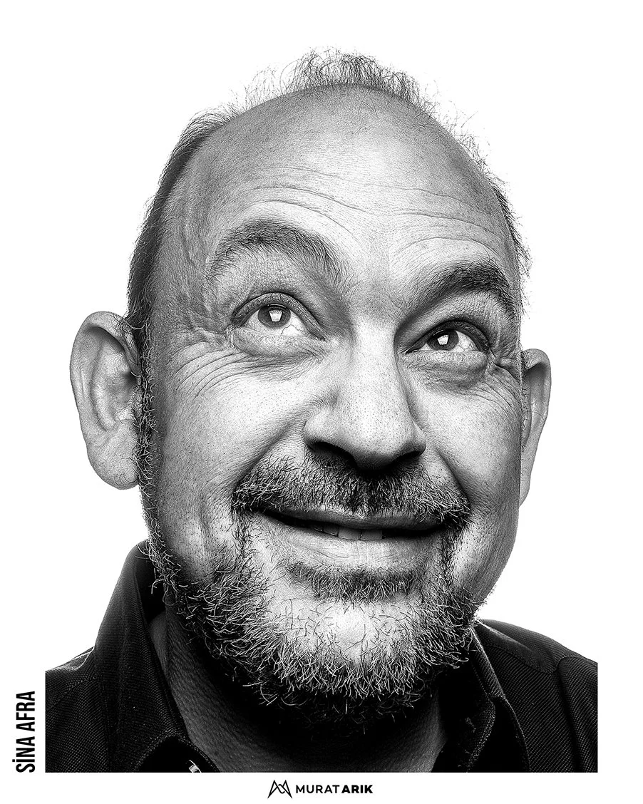 Black and white portrait of a middle-aged man with a beard, smiling and looking upward.