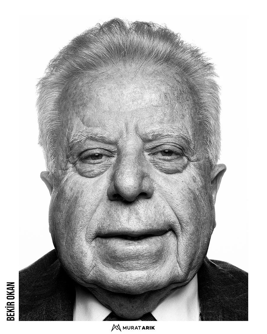 A black-and-white portrait of an elderly man with gray hair, wearing a suit and tie.