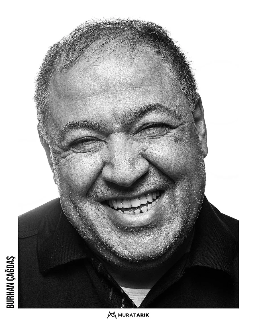 Black and white close-up photo of a middle-aged man with short hair smiling broadly, showing teeth, and eyes squinting from laughter or happiness.