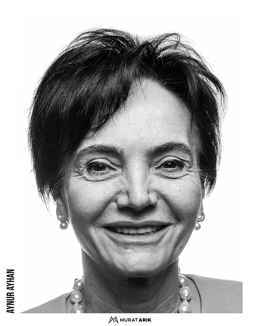 Black and white portrait of a smiling older woman with short dark hair, wearing pearl earrings and a pearl necklace.
