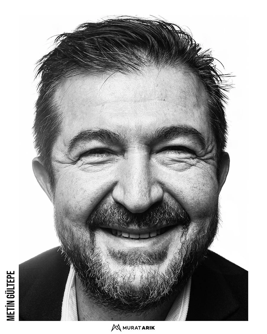 Black and white portrait of a smiling middle-aged man with facial hair and short, dark hair, wearing a dark blazer and light shirt.