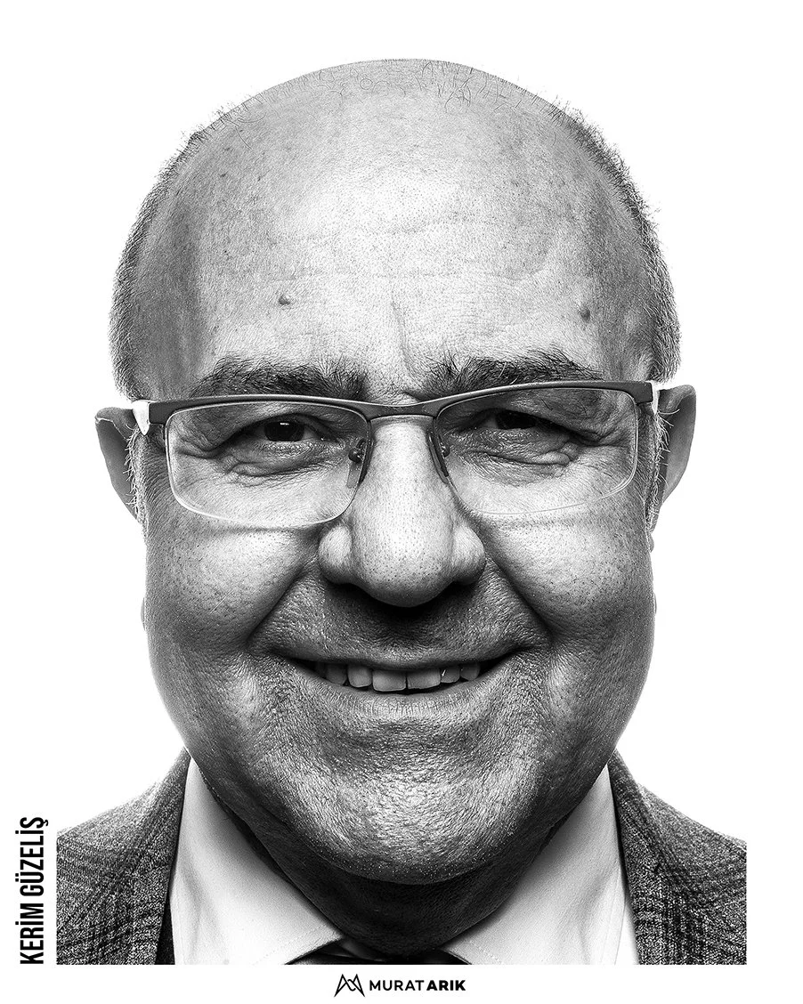 Close-up black-and-white portrait of a smiling man with glasses, wearing a suit and tie.