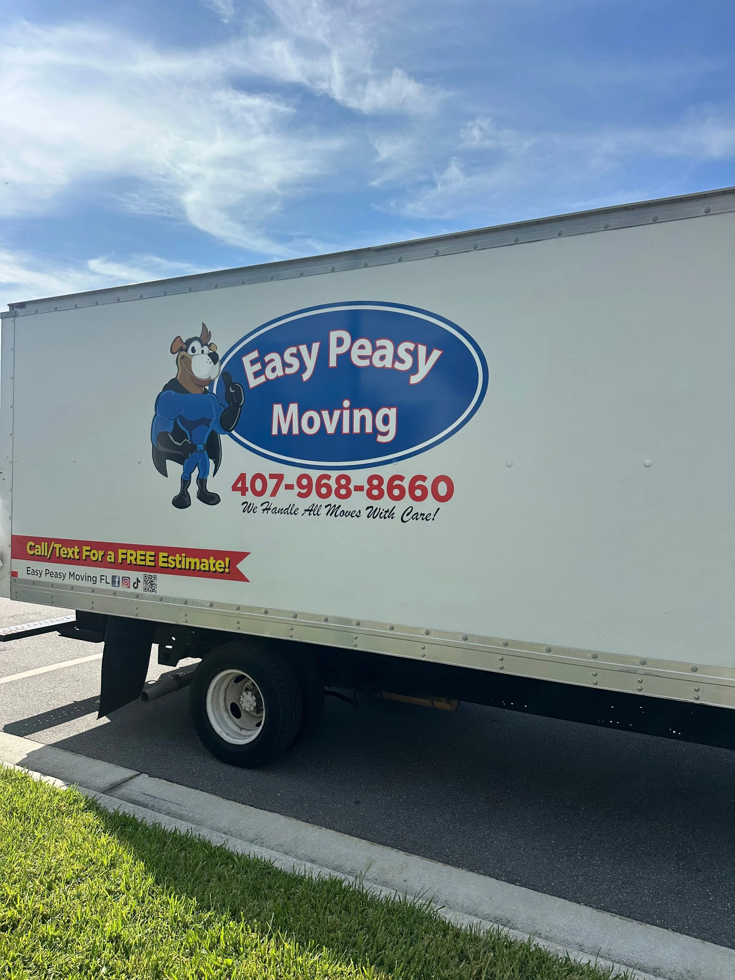 White moving truck with a cartoon animal mascot wearing a superhero costume, the truck advertises Easy Peasy Moving, LLC, a moving company, with a phone number and tagline in Central Florida.