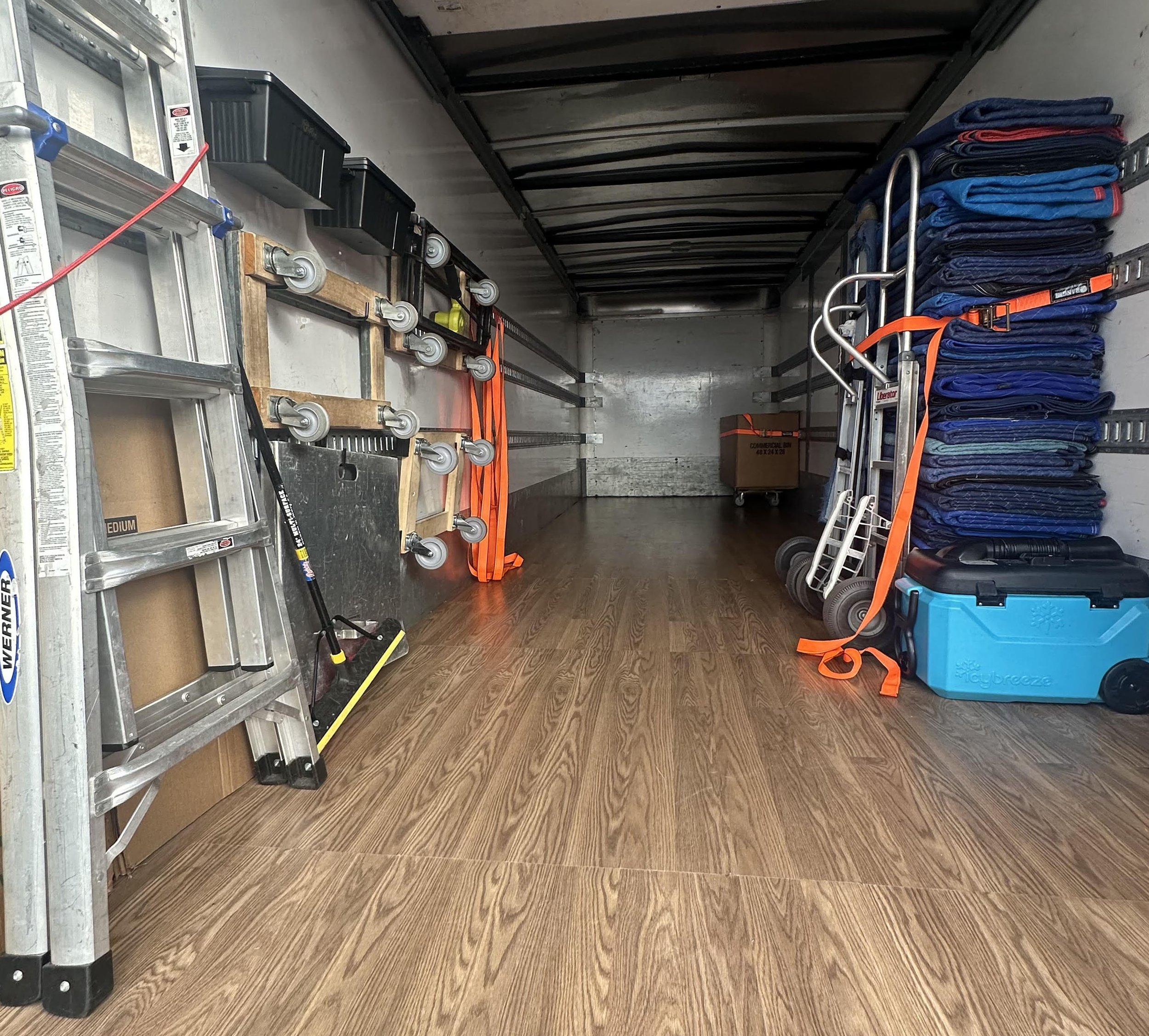 Inside an Easy Peasy Moving, LLC moving truck with tools and moving supplies, including a ladder, a broom, dollies, moving blankets, and a box in Central Florida.