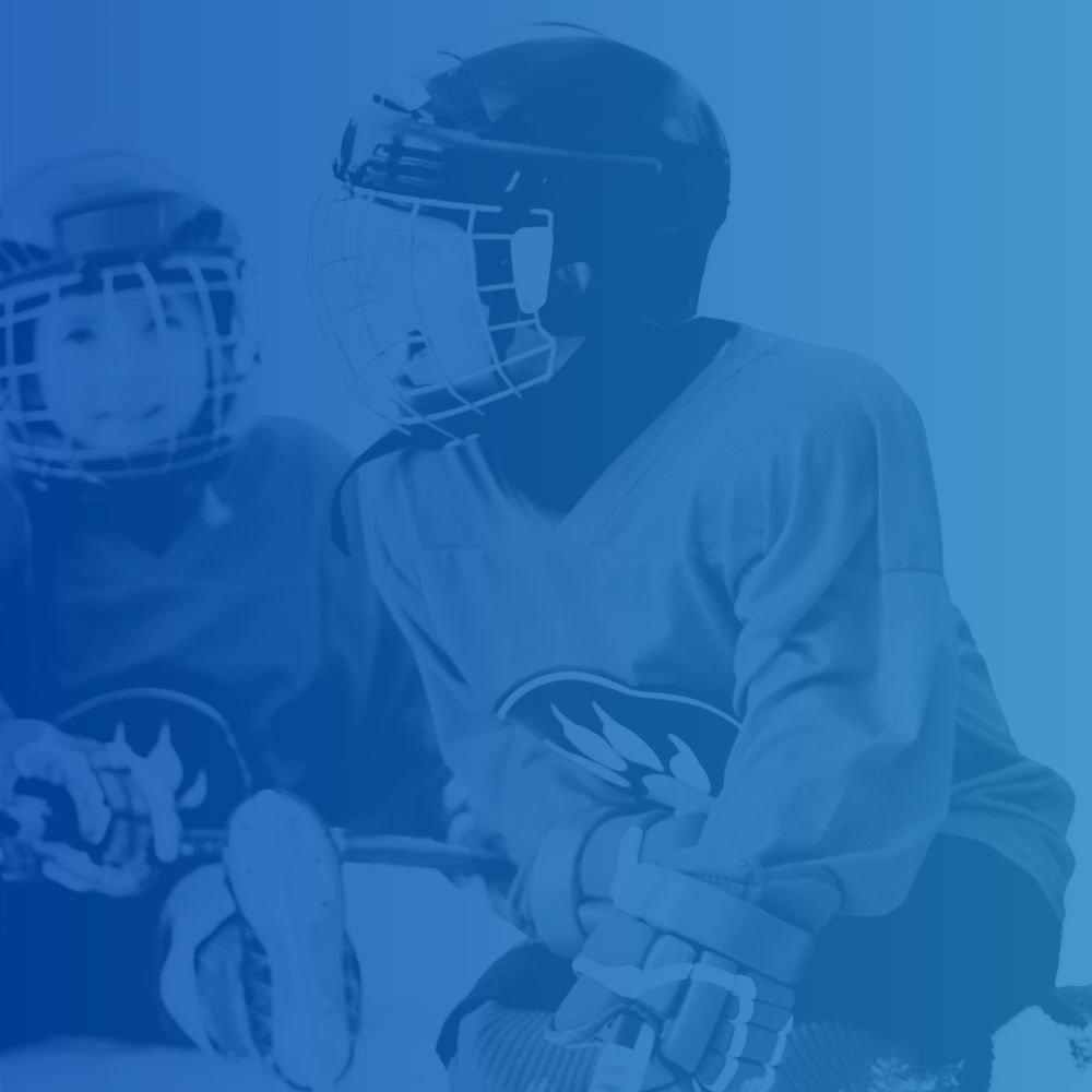 Two ice hockey players wearing protective helmets and uniforms, one of whom appears to be coaching or communicating during the game.