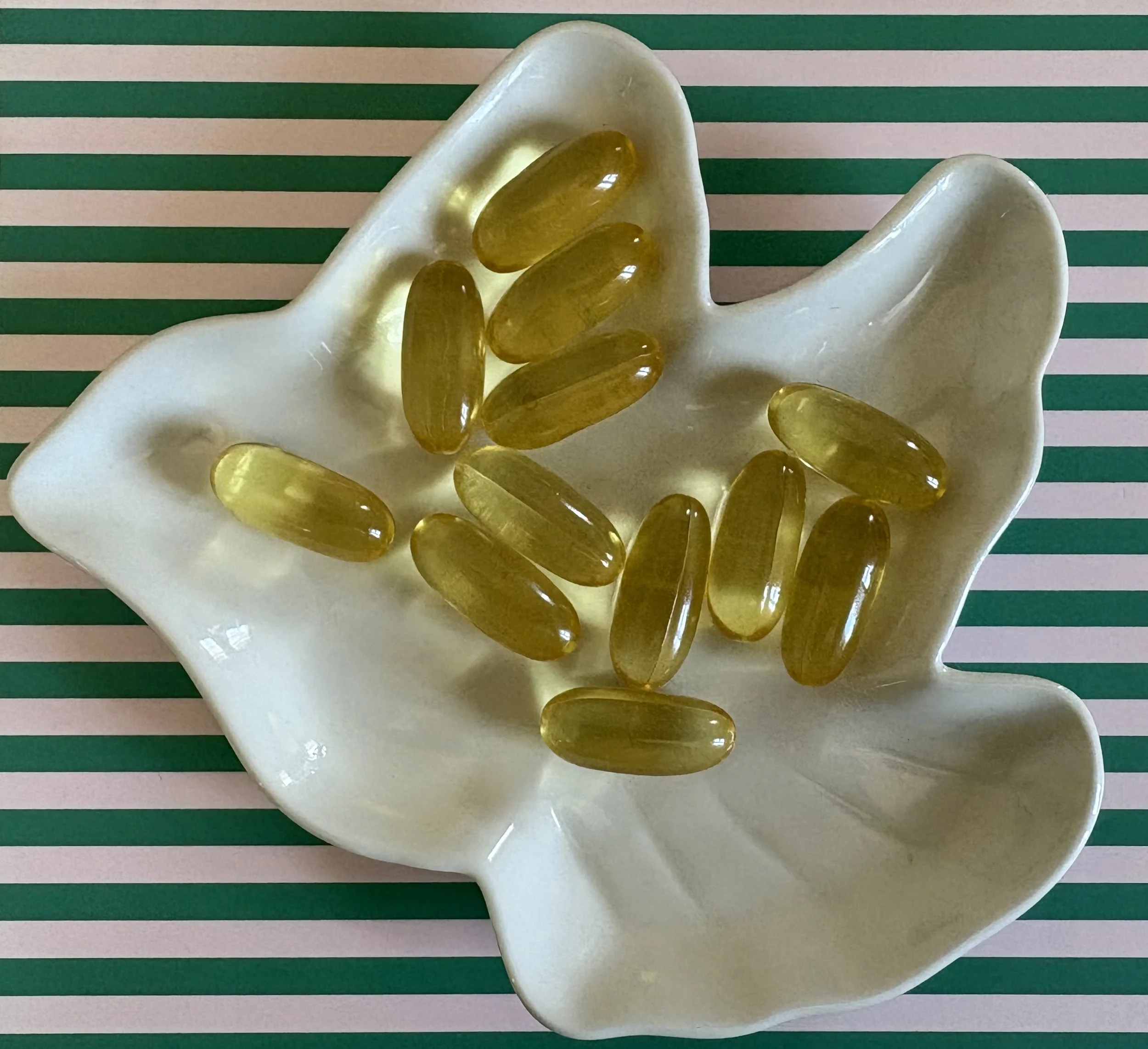 Gelules d'Oméga-3 d'EPA et DHA. Supplémentation, posée sur une coupelle en céramique blanche représentant une colombe