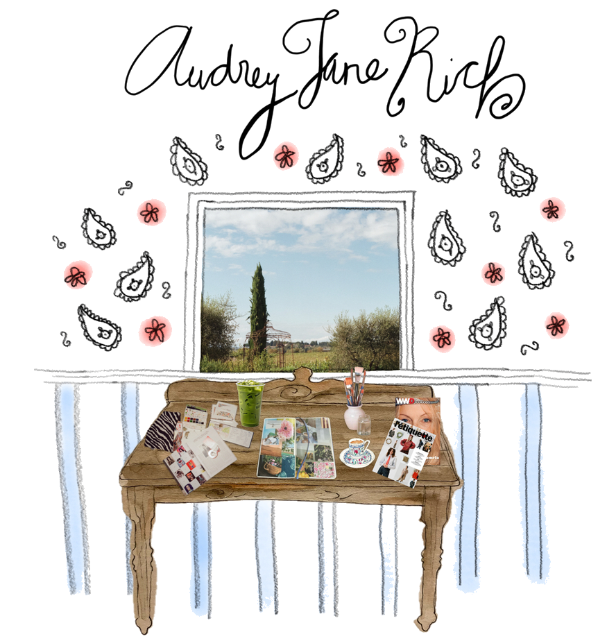 Decorative illustration of a window with a view of outdoors, a wooden desk with magazines, a green drink, and various stationery items. The wall has illustrated teardrop shapes, pink flowers, and cursive text reading "Audrey Jane Rich" at the top.