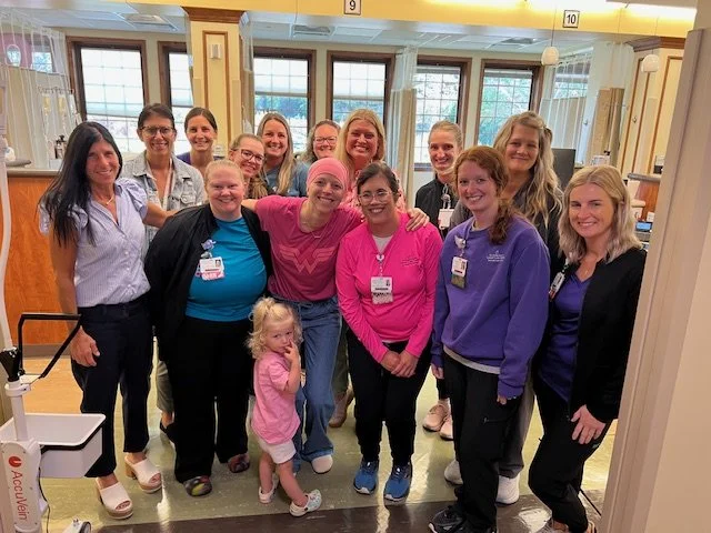 Group of women and one young girl smiling and posing together in a hospital or clinic waiting area.