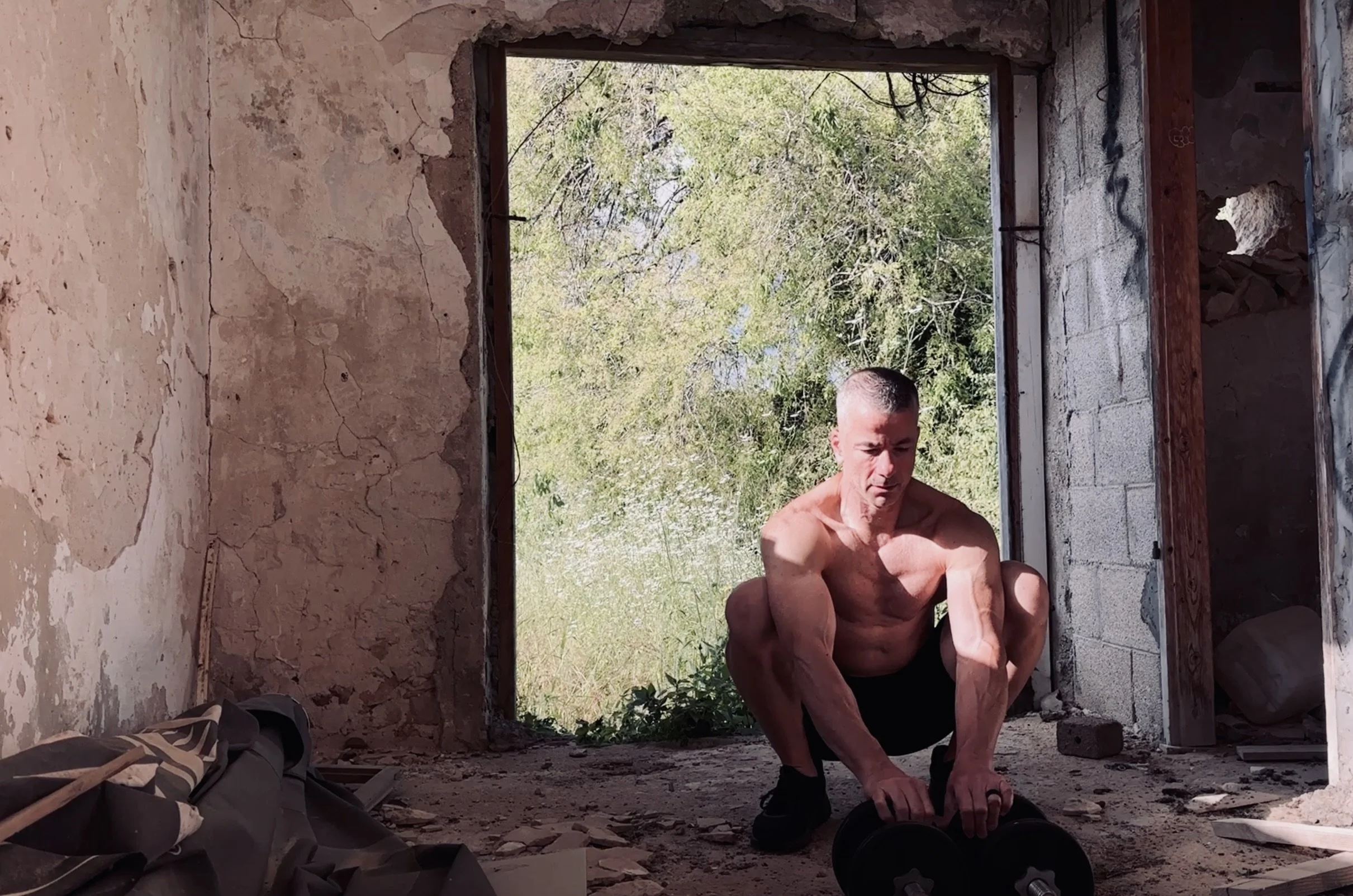 man in a deep squat position with the sun shining on him