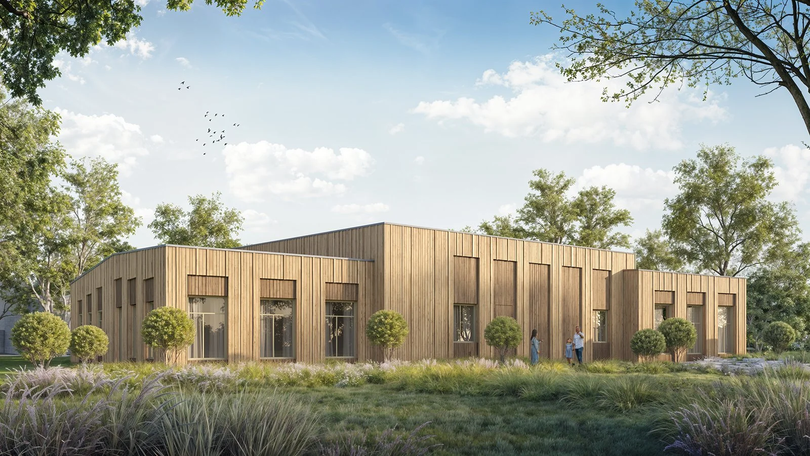 A modern wooden building with large windows, surrounded by trees and landscaped greenery, with a clear sky and a small group of people outside.