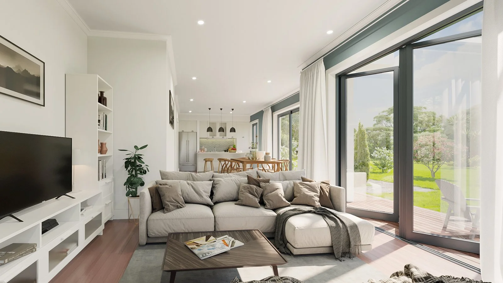 Bright living room with large sliding glass doors opening to a lush outdoor garden, beige sofa with multiple pillows, wooden coffee table with magazines, white wall-mounted TV, bookshelf with decor, and an open kitchen and dining area in the backgrou