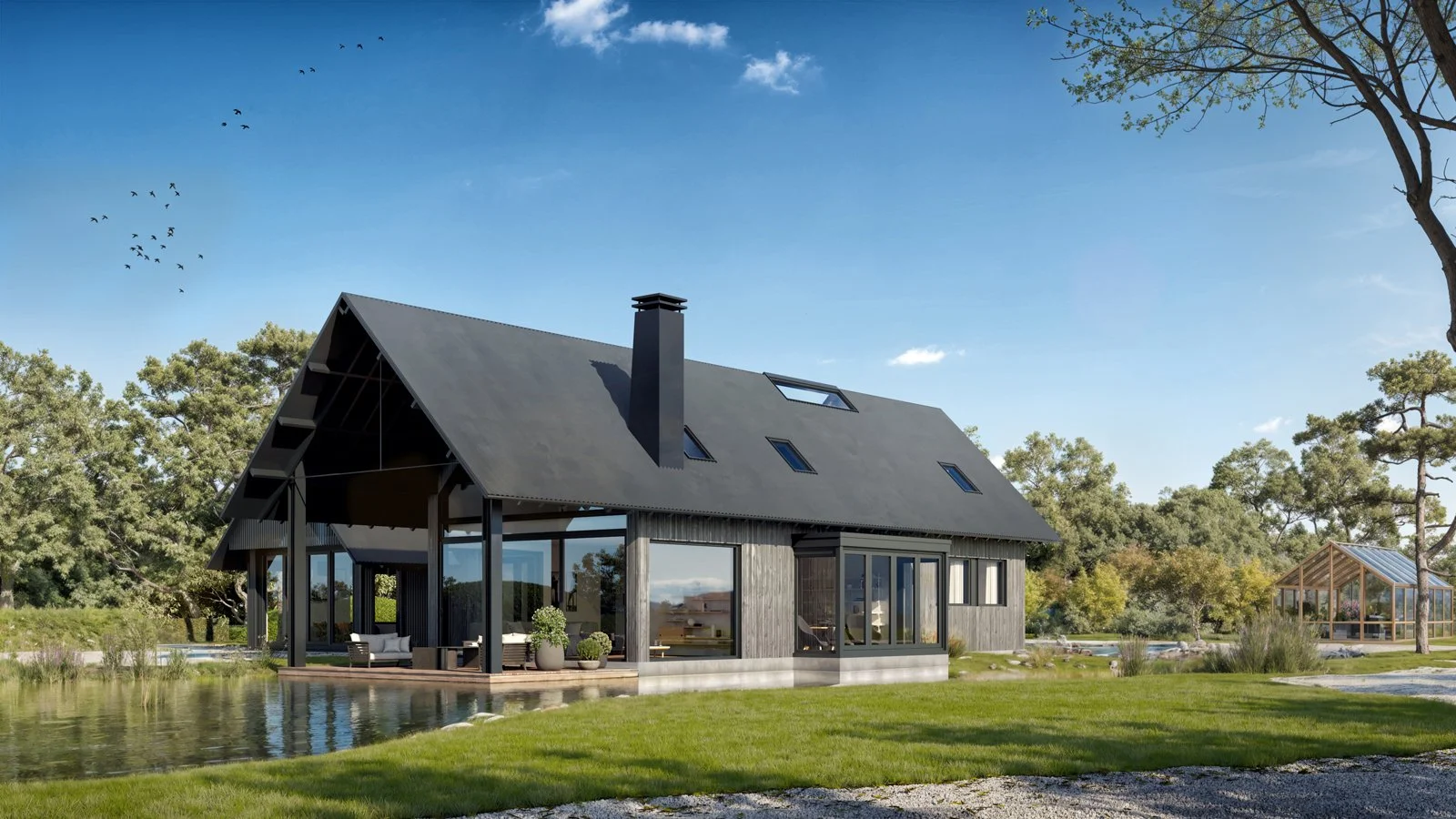 Modern house with large windows and a black roof, situated near a pond, surrounded by trees and greenery on a clear day.