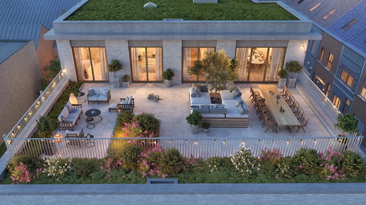 An outdoor rooftop terrace in an urban setting, featuring outdoor seating, a dining table, potted plants, and landscaped garden with colorful bushes and trees, enclosed by a white railing, during evening lighting.