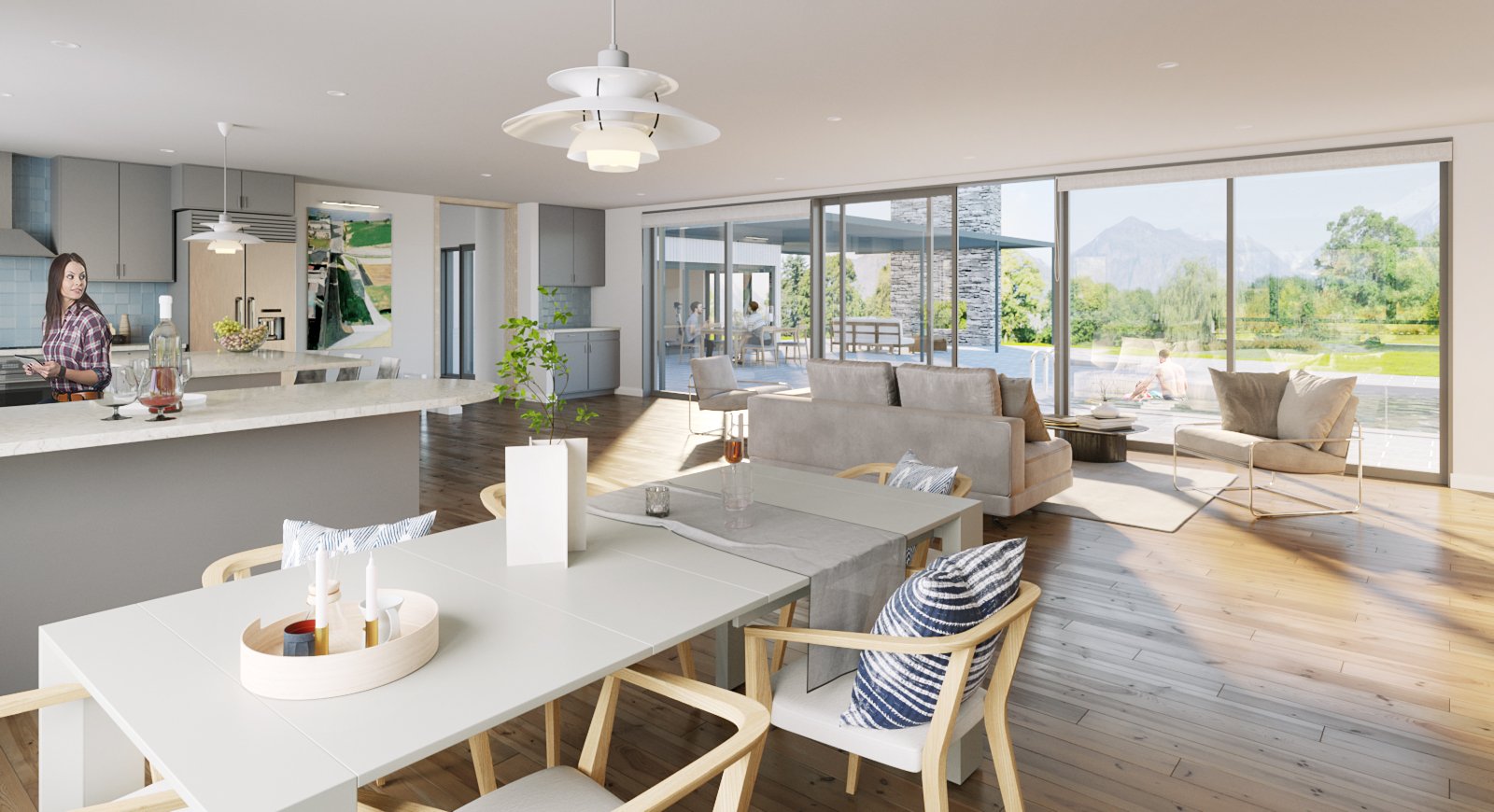 Open-concept living room and kitchen with large glass sliding doors overlooking a lakeside outdoor patio and scenic mountains in the distance. Furniture includes a dining table with chairs, a sofa, and lounge chairs, with decor like candles, plants, 
