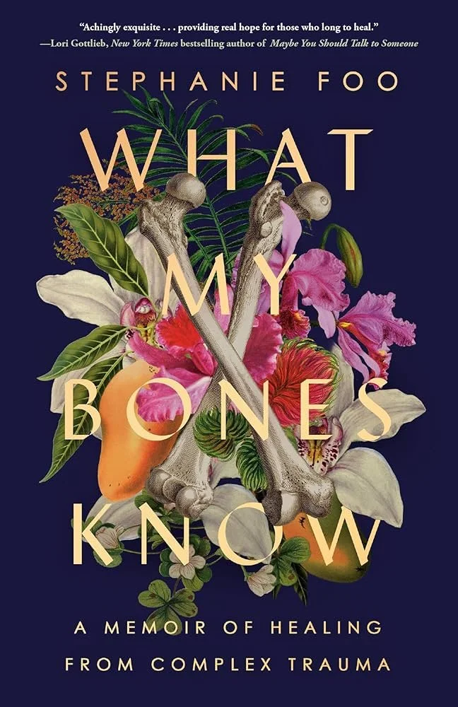 Book cover titled 'What My Bones Know: A Memoir of Healing from Complex Trauma' by Stephanie Foo. Features an illustration of various flowers, leaves, mushrooms, a carrot, and two crossed bones on a dark background.