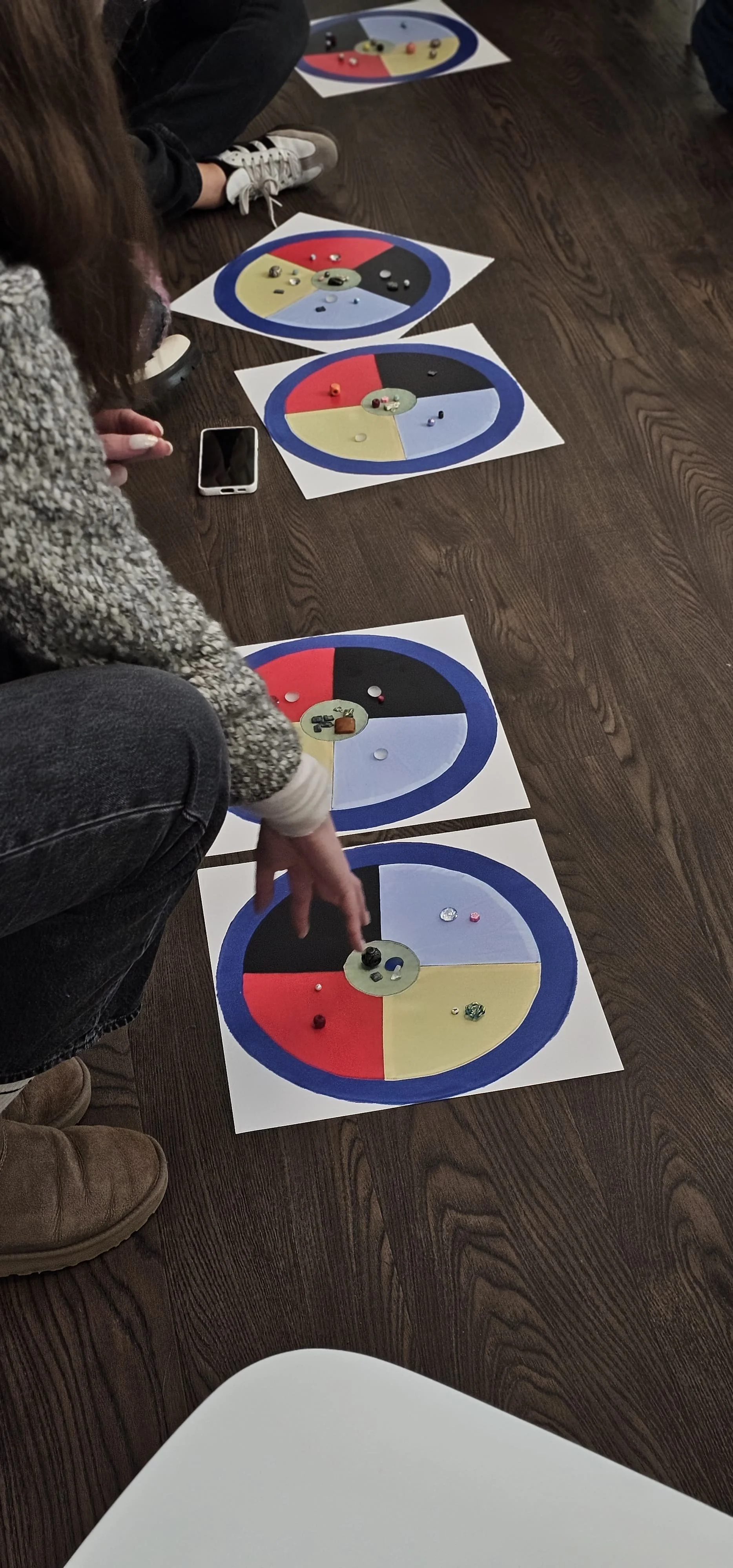 Children playing a ring toss game with painted circular boards on a wooden floor.