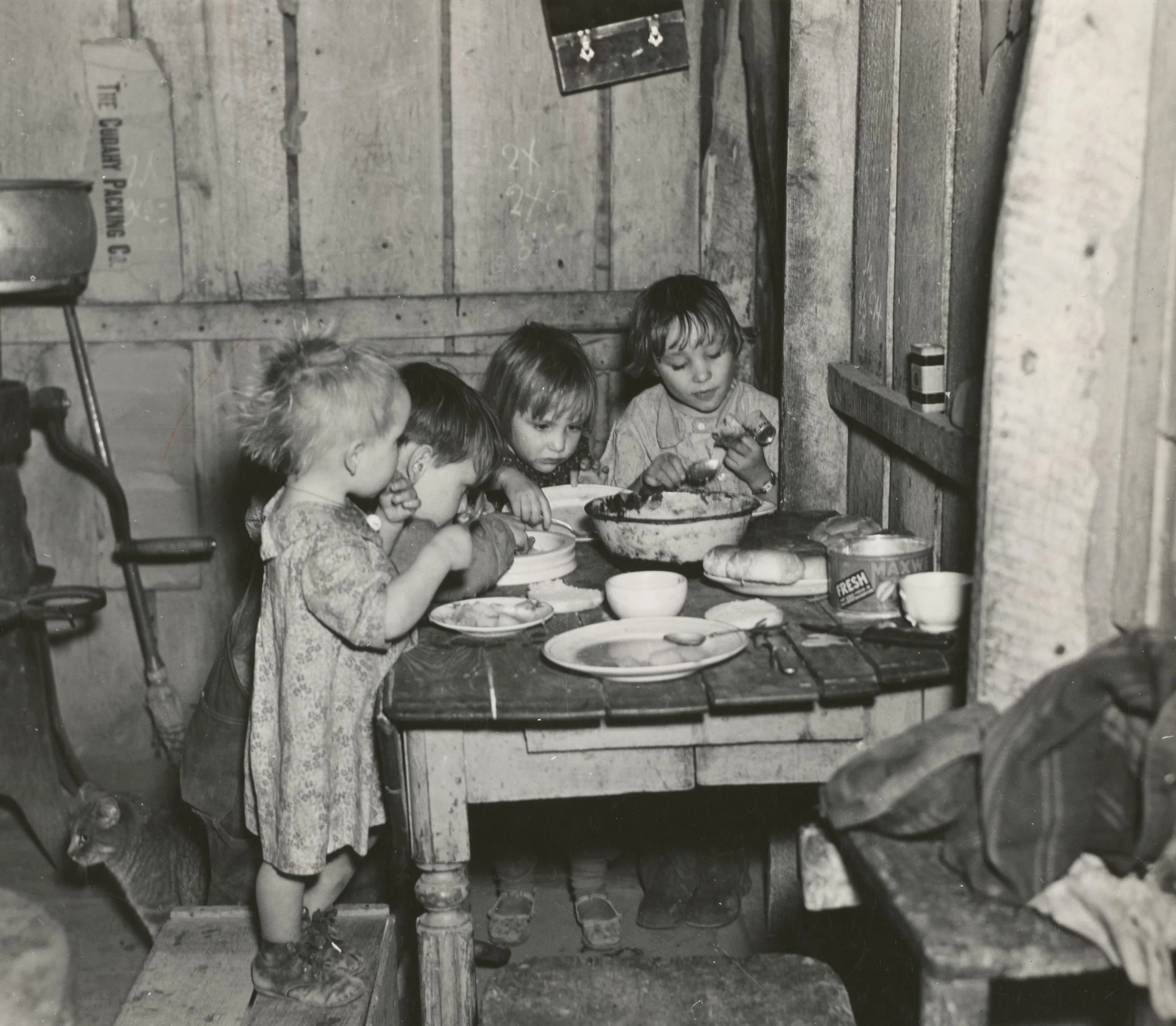 black and white historical photo of children eating at a table