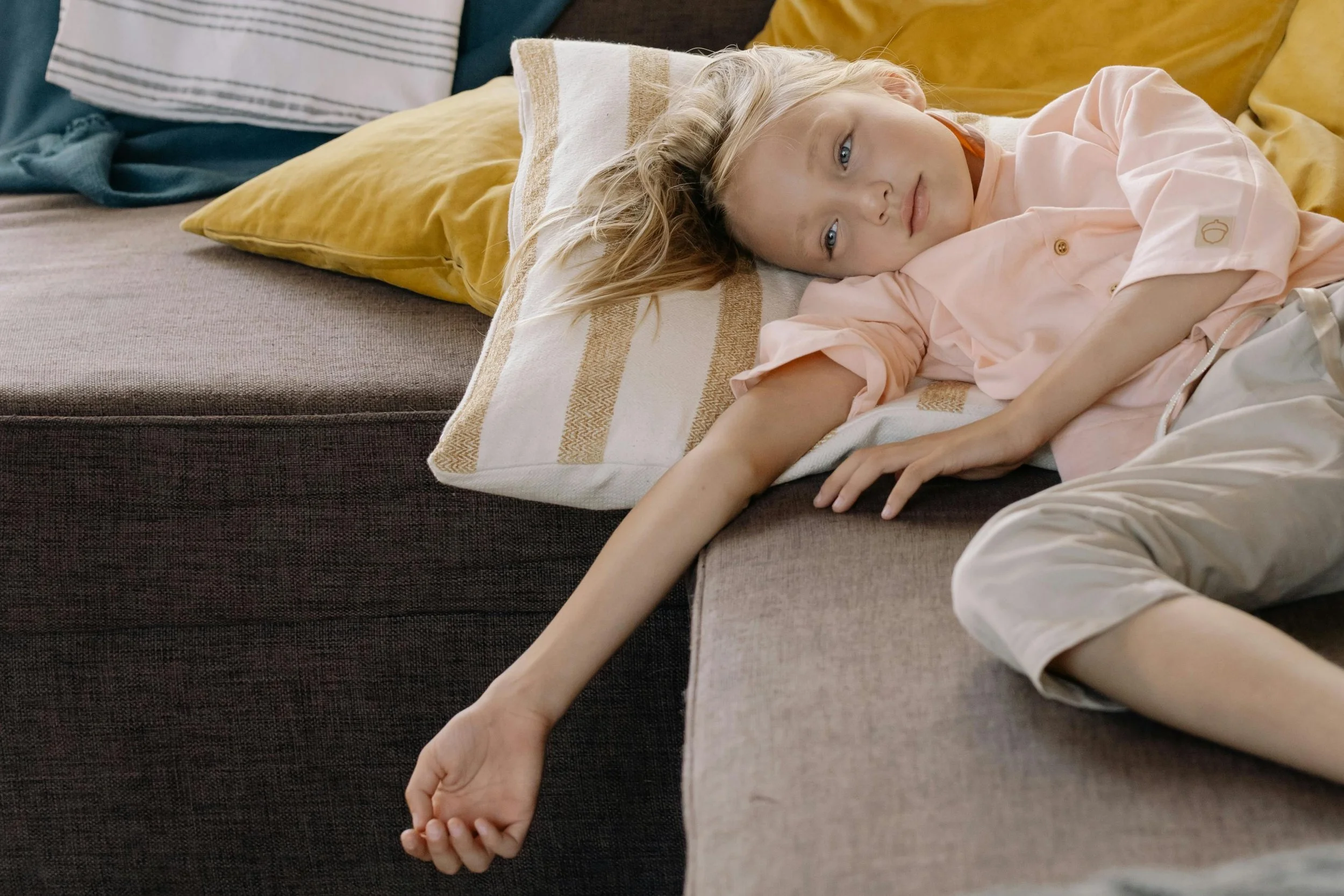 young girl lays tired on a sofa