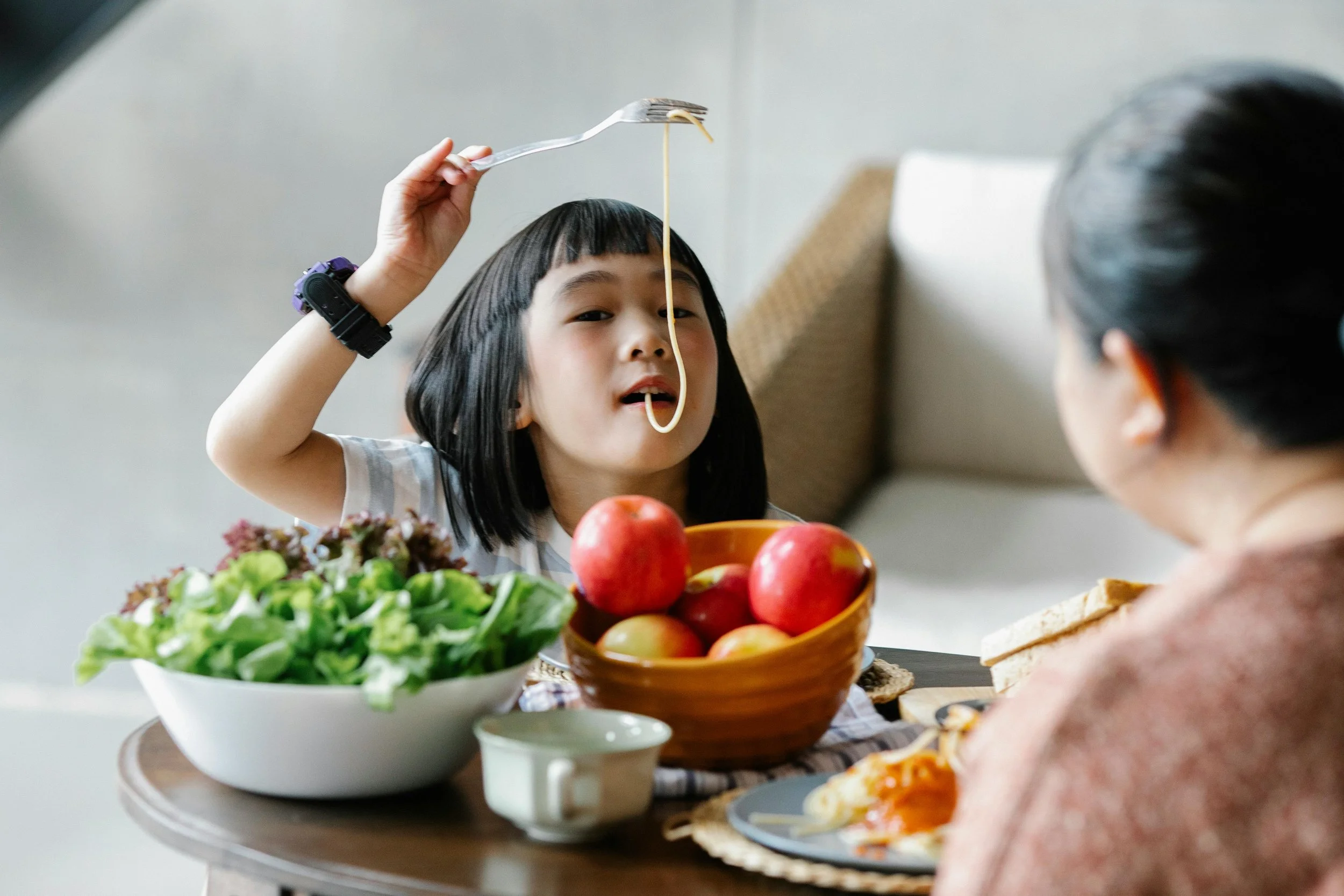 Little girl eating spaghetti with a fork