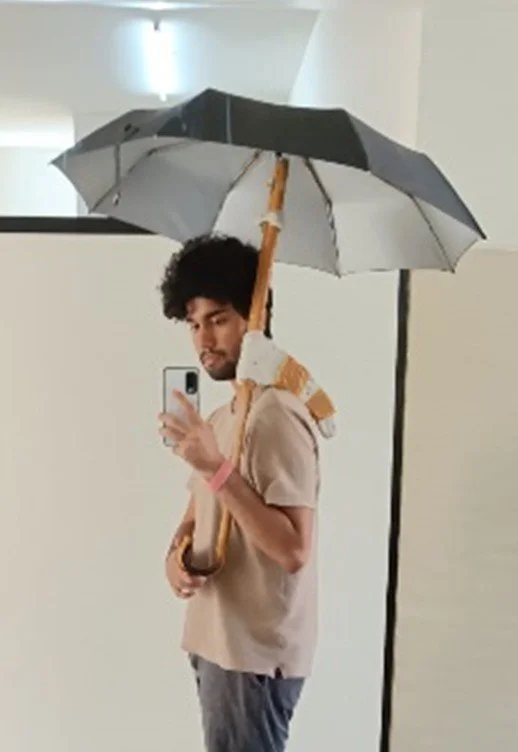 Young man taking a selfie in front of a mirror, holding a black and white umbrella.
