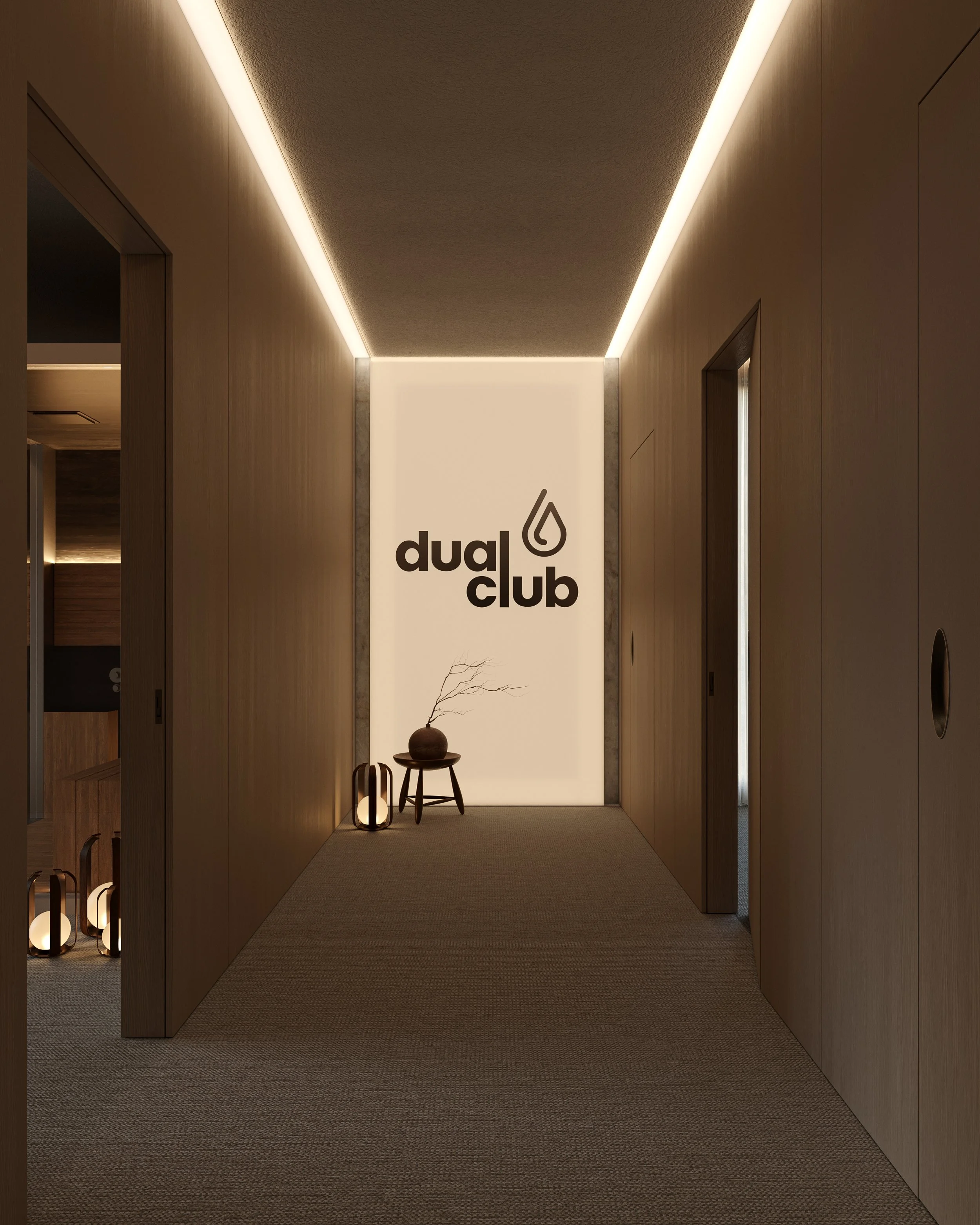 Corredor de um clube com iluminação indireta no teto e uma parede com logo 'dual club'. Ao lado, objetos decorativos como uma planta seca em um vaso e luminárias decorativas.
