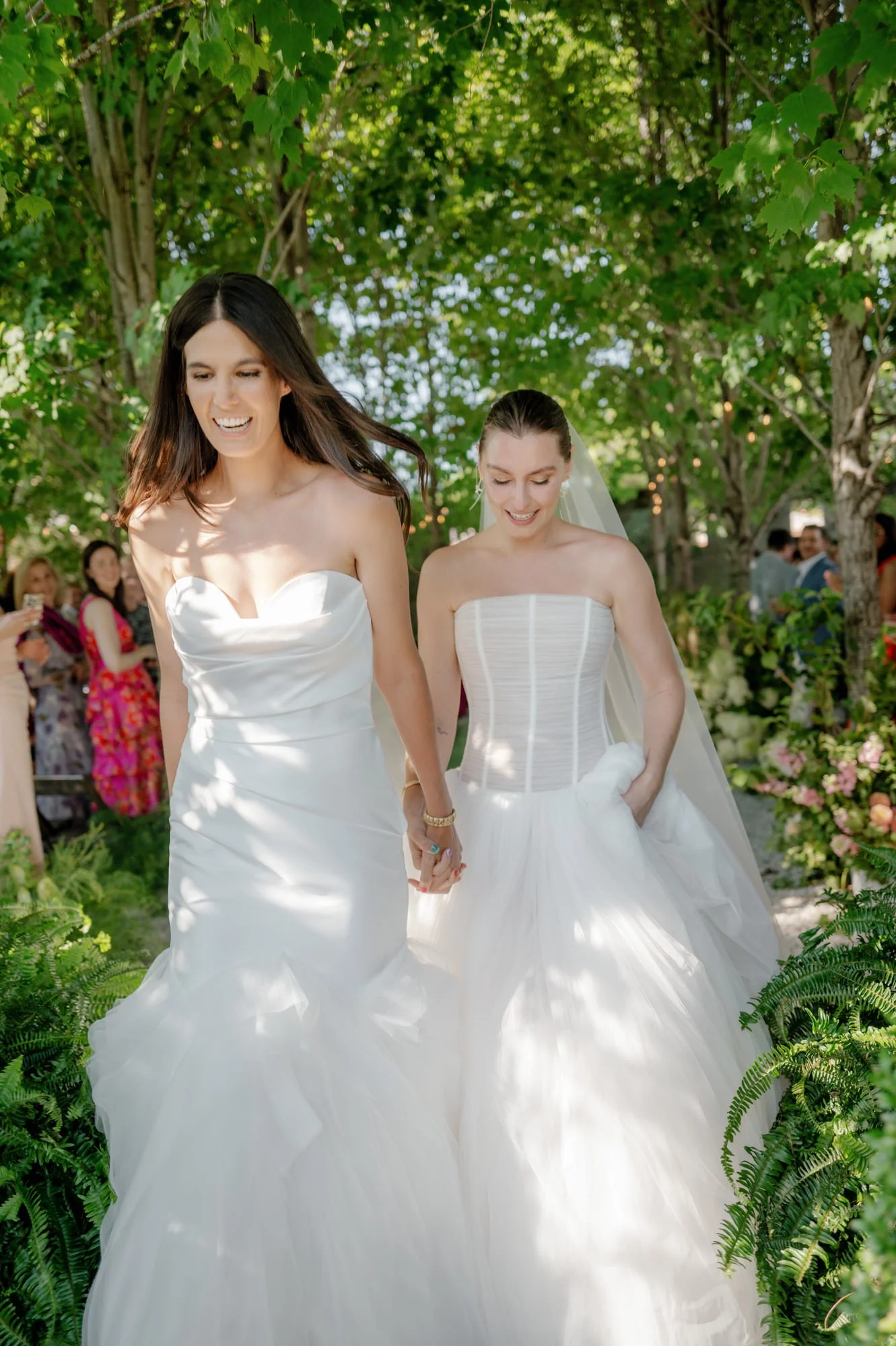 Brides exiting the ceremony smiling beneath tree canopies at Valley Rock Inn in Sloatsburg, photographed by Jenny Fu.