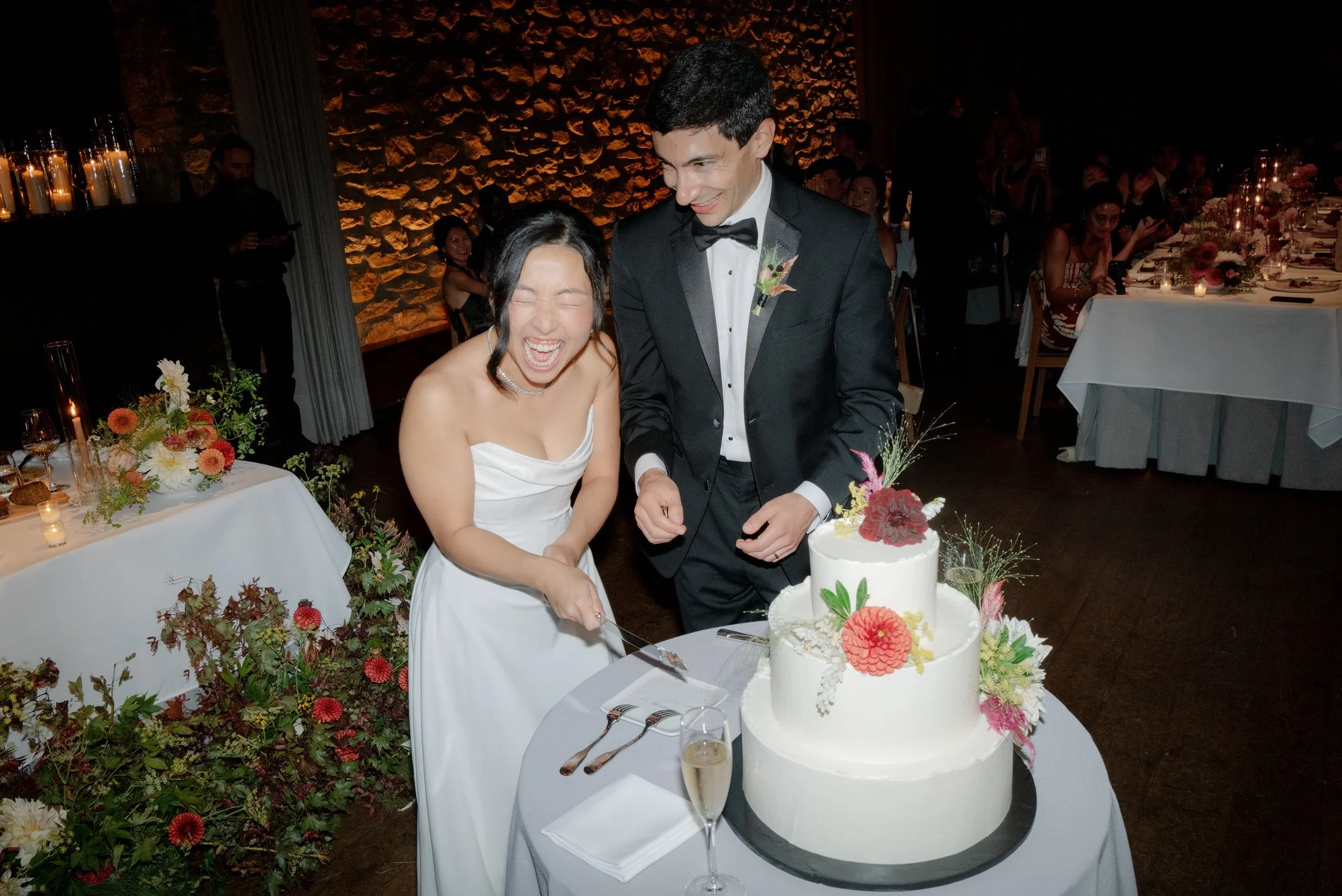 Bride and groom laughing as they cut the wedding cake during the reception at Blue Hill at Stone Barns, photographed by Jenny Fu.