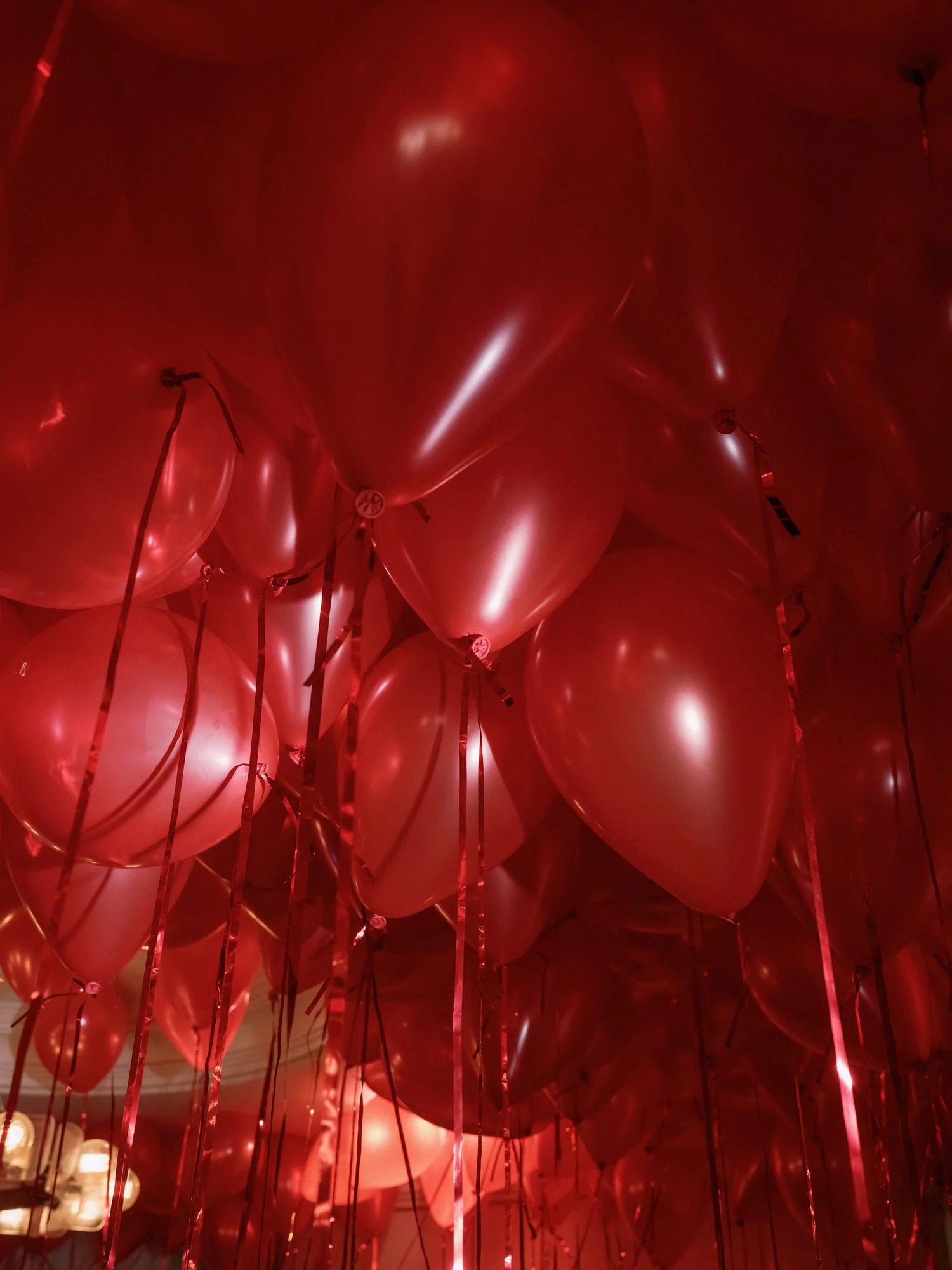 Ceiling filled with red balloons and ribbon streamers at a Waldorf Astoria New York wedding celebration, photographed by Jenny Fu.