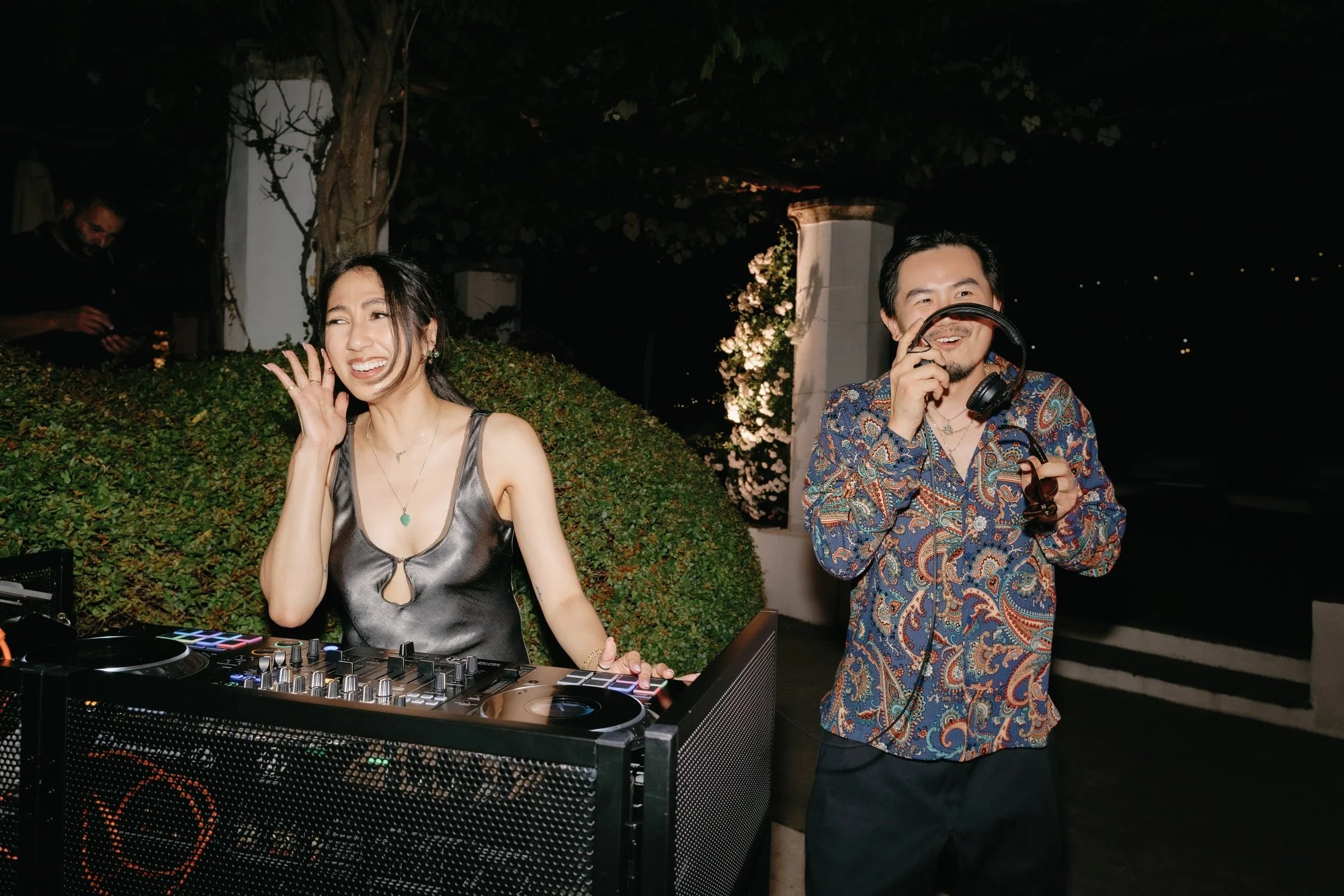 Two DJs smiling behind the booth during the lively wedding reception at Caruso, A Belmond Hotel in Ravello, Italy, photographed by Jenny Fu.