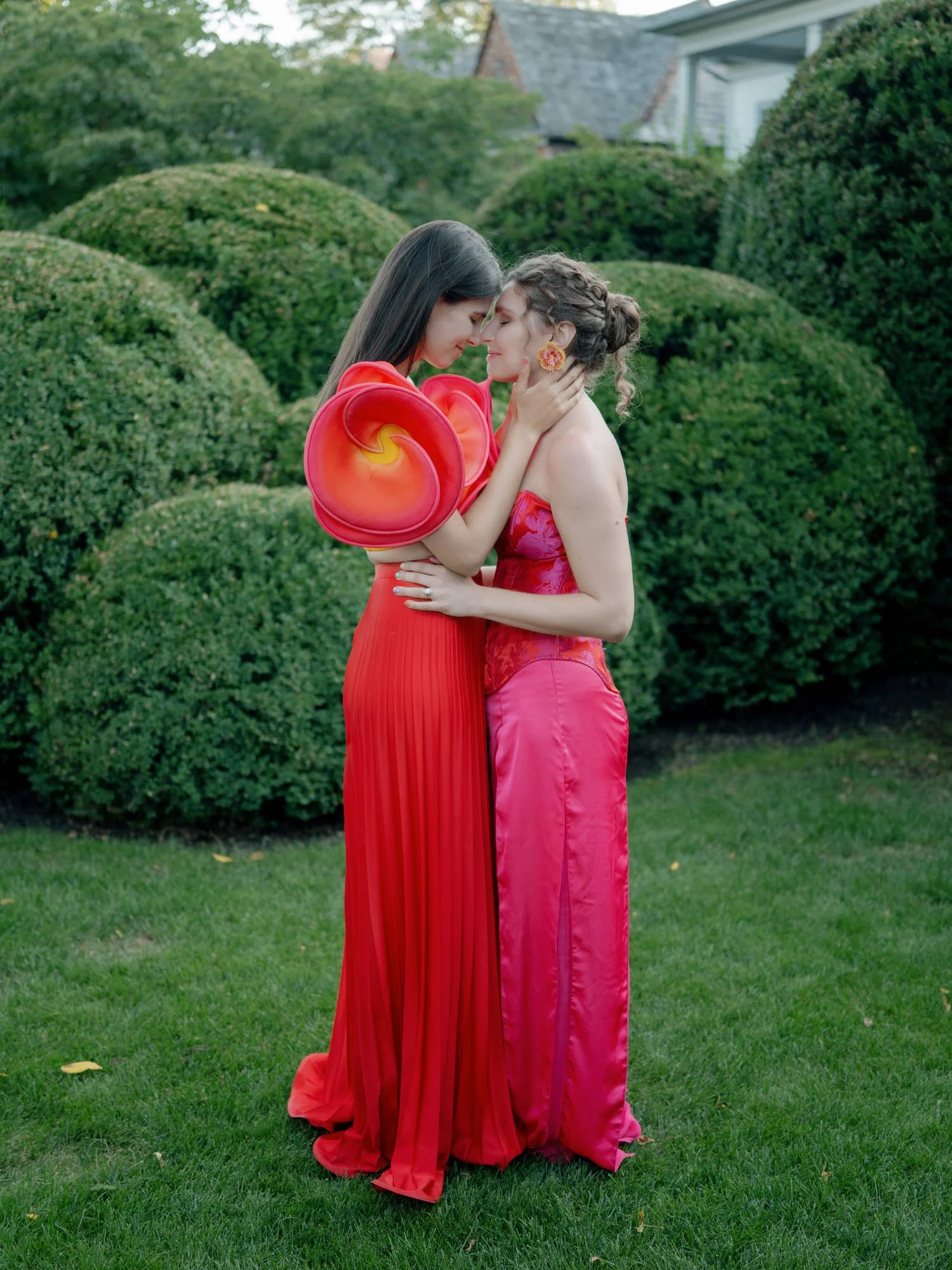 Two brides embracing in the sculpted garden at Valley Rock Inn, Sloatsburg, NY, photographed by Jenny Fu.