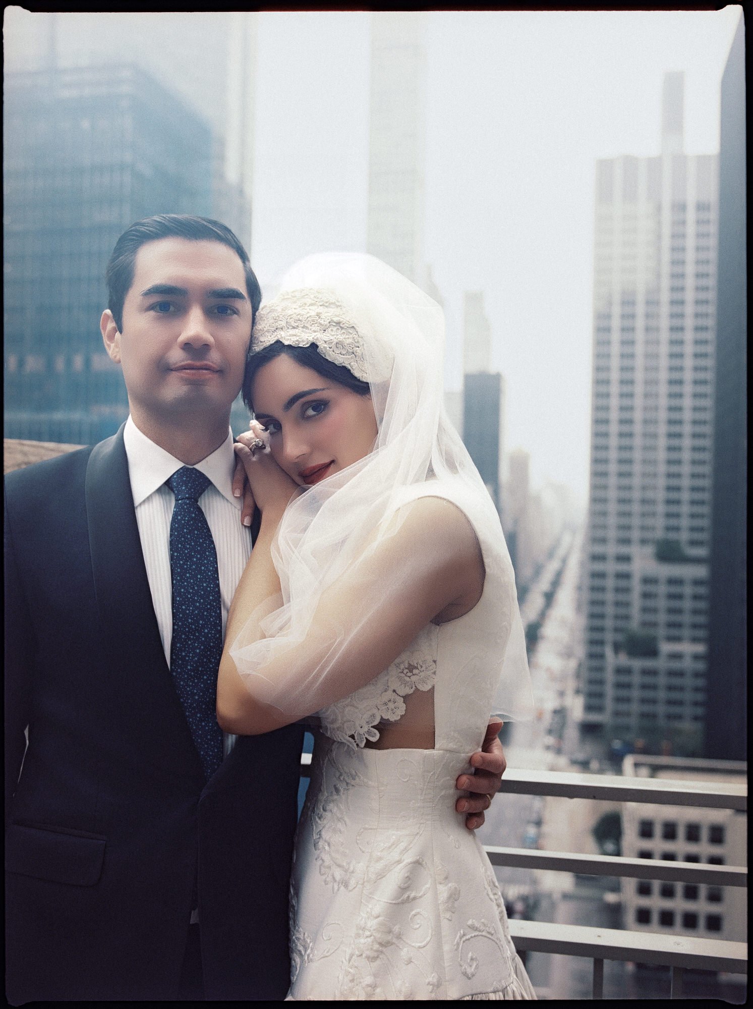 Bride nestling into her groom on a terrace with the Midtown skyline above Park Avenue behind them at the Waldorf Astoria New York, photographed by Jenny Fu.