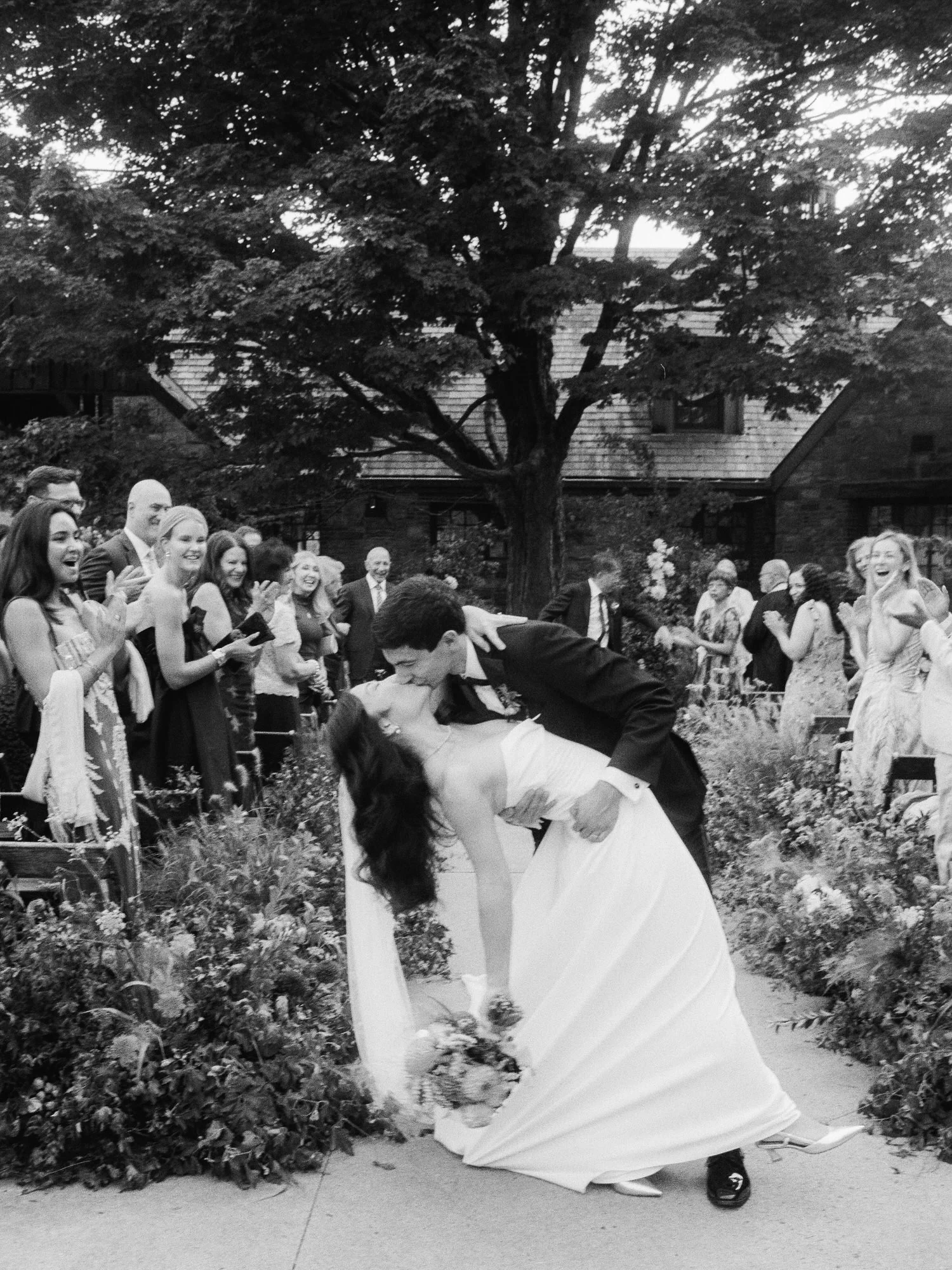 Dip kiss in the aisle as guests cheer during the recessional in black and white at Blue Hill at Stone Barns, photographed by Jenny Fu.