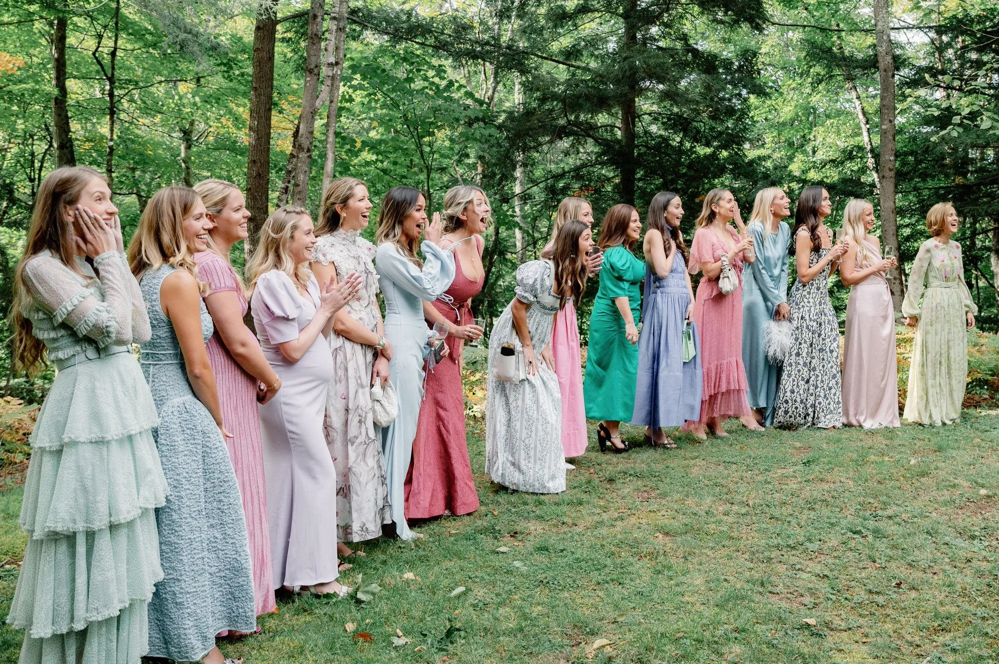 Bridesmaids in colorful gowns reacting with excitement during a first look moment at the Ausable Club in the Adirondacks