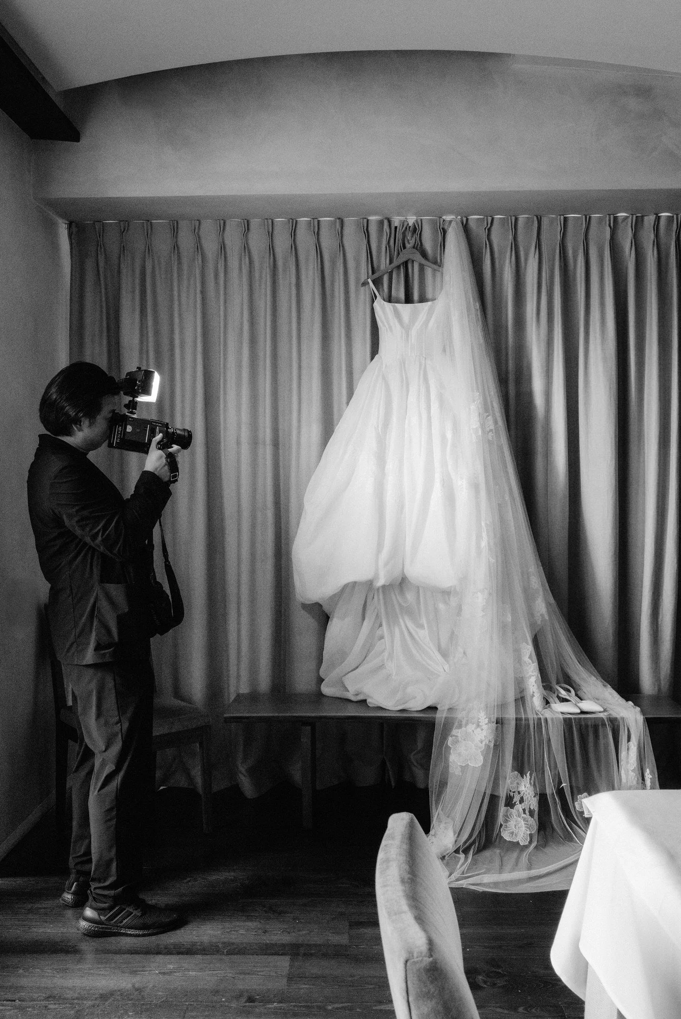 Film videographer capturing Super 8 footage of the bride’s gown and veil displayed against soft drapery at Blue Hill at Stone Barns in Pocantico Hills, New York, photographed by Jenny Fu.