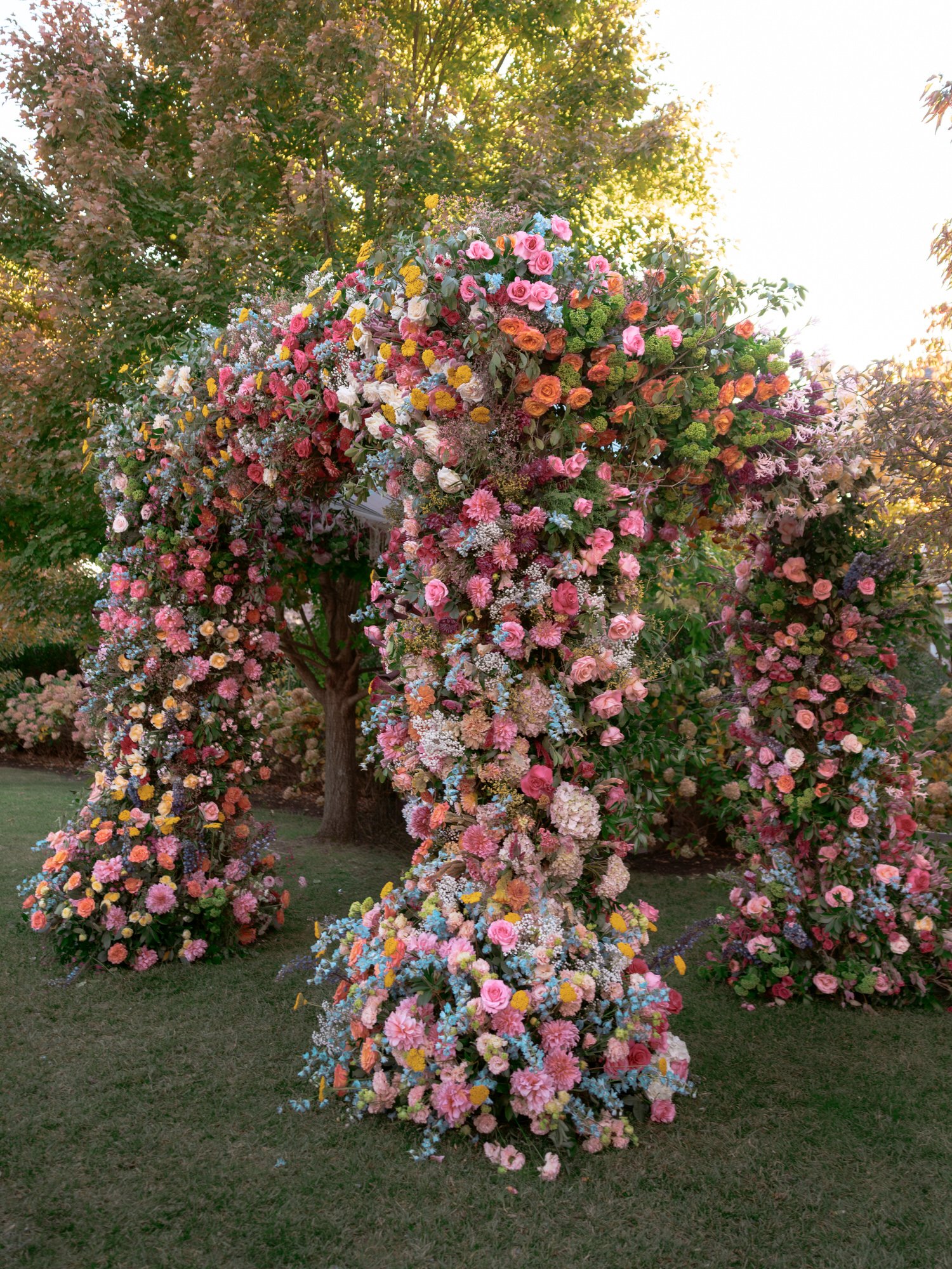 Vibrant floral chuppah filled with colorful seasonal blooms under afternoon light at Valley Rock Inn in Montvale, New Jersey, photographed by Jenny Fu.