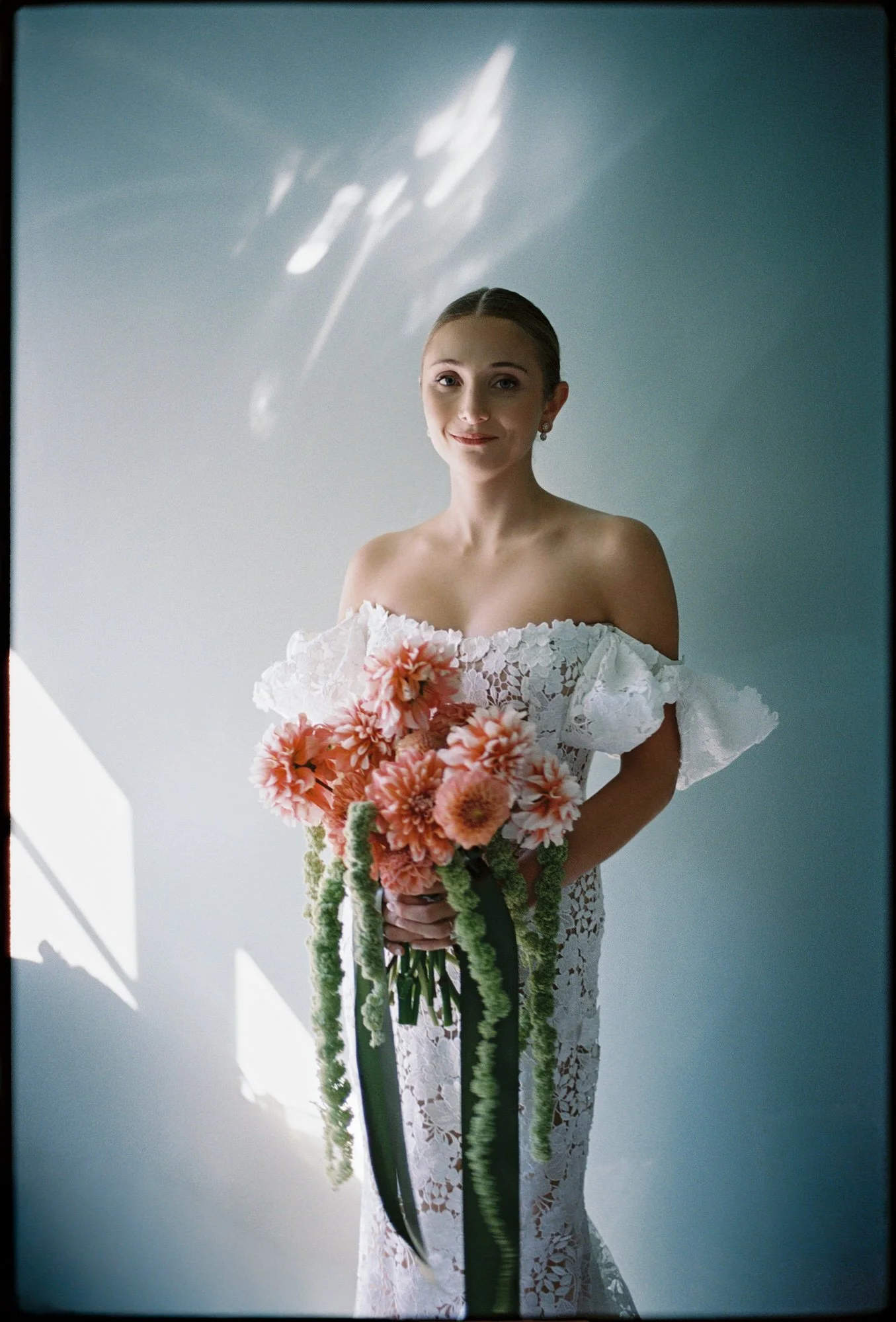 Portrait of the bride gazing upward in her lace gown against a softly lit wall at Troutbeck in Amenia, photographed by Jenny Fu.