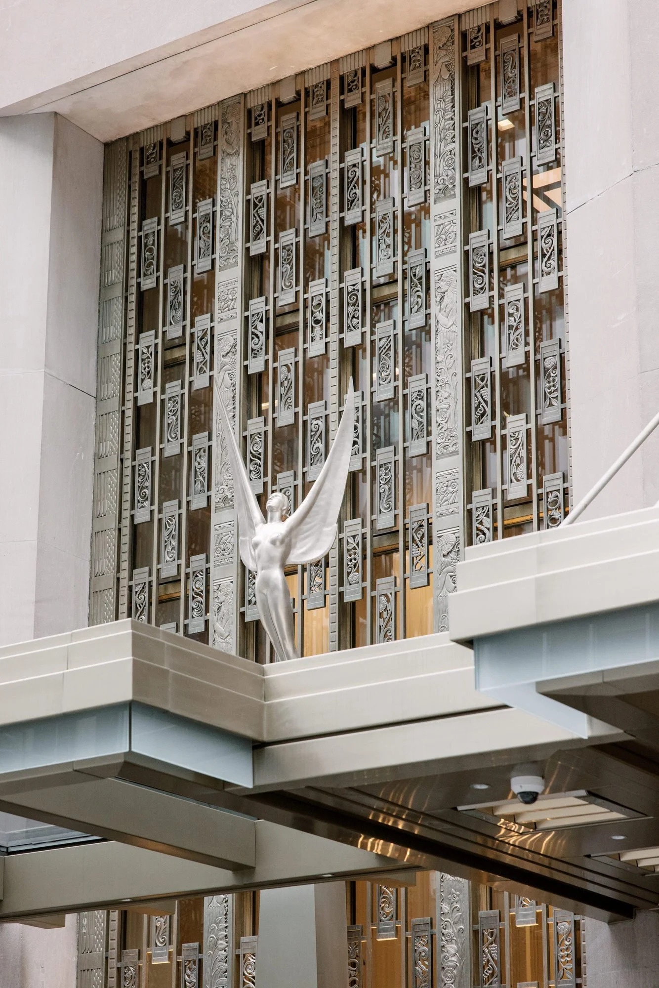 Art Deco metalwork and winged statue above the entrance of the Waldorf Astoria New York, photographed by Jenny Fu.