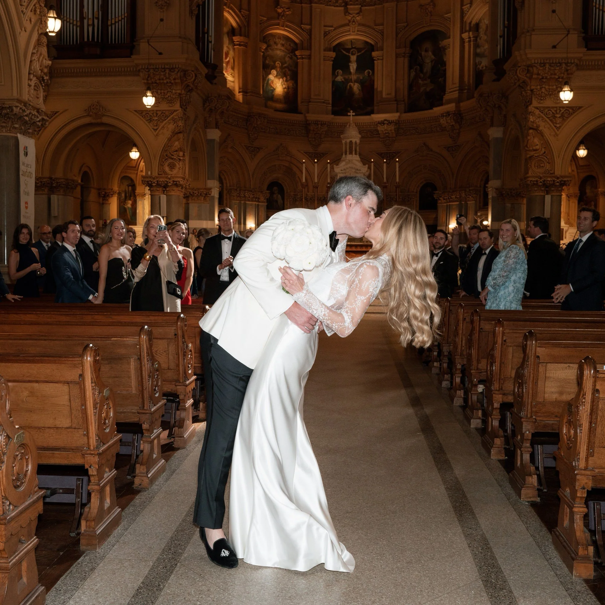 Groom dips his bride for a kiss down the church aisle surrounded by guests at St. Francis Xavier Church in Chelsea, photographed by Jenny Fu.