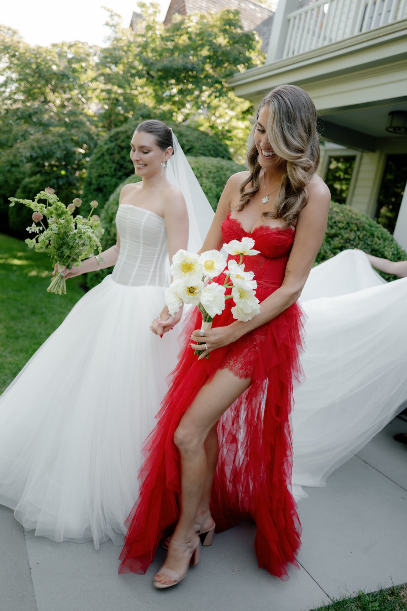 Bride and bridesmaid walking hand in hand with bouquets and the bride’s train trailing behind at Valley Rock Inn in Sloatsburg, photographed by Jenny Fu.