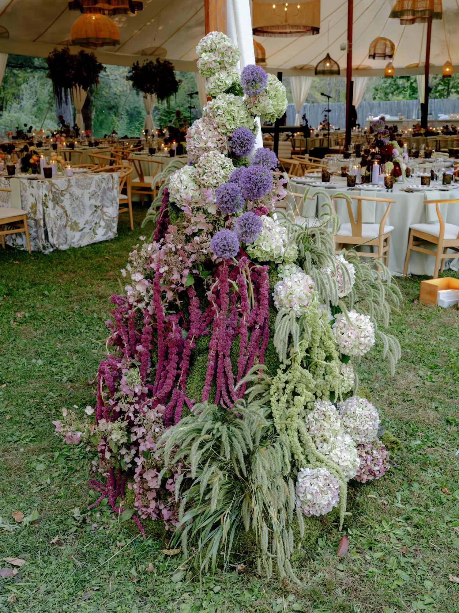Tall floral installation of hydrangeas and trailing amaranthus beside the tented reception at Troutbeck in Amenia, New York, photographed by Jenny Fu.