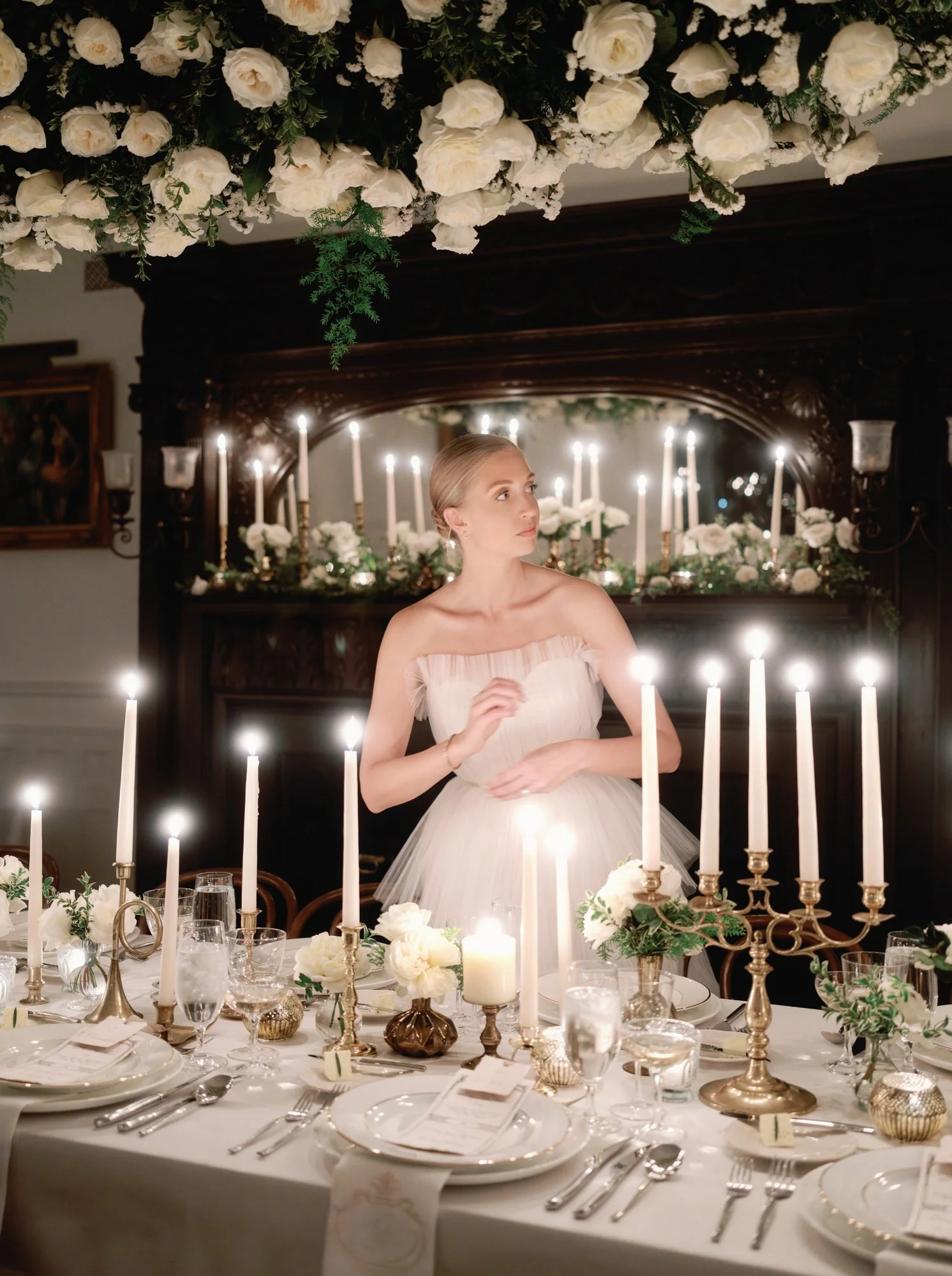 Bride in a strapless tulle gown surrounded by candlelight and white florals at an intimate dinner table, photographed by Jenny Fu.