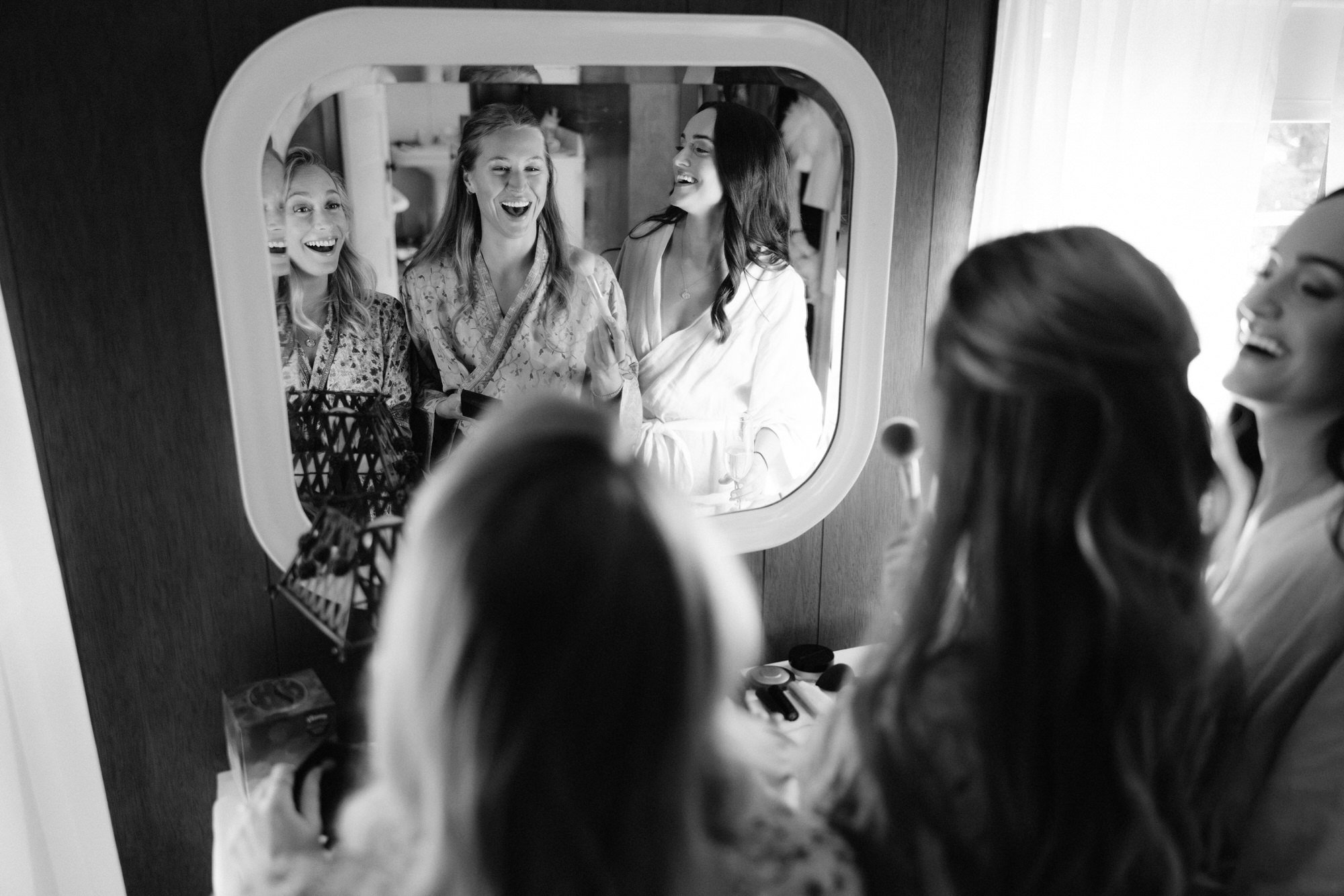 Olivia laughing with her bridesmaids while getting ready on the wedding morning at the Ausable Club in the Adirondacks