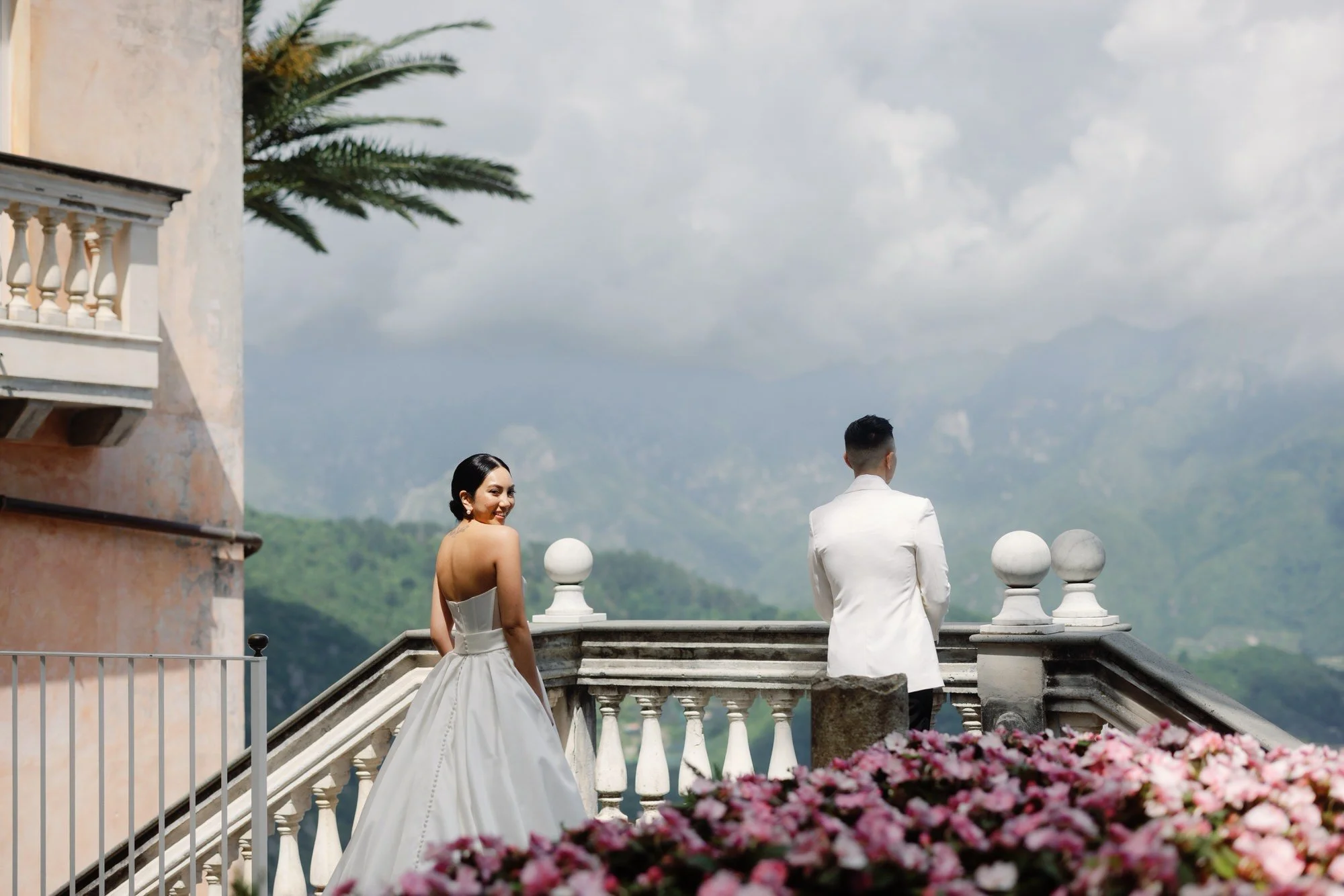 Bride approaching the groom for their first look on the flower-lined terrace at Caruso, A Belmond Hotel in Ravello, Italy, photographed by Jenny Fu.