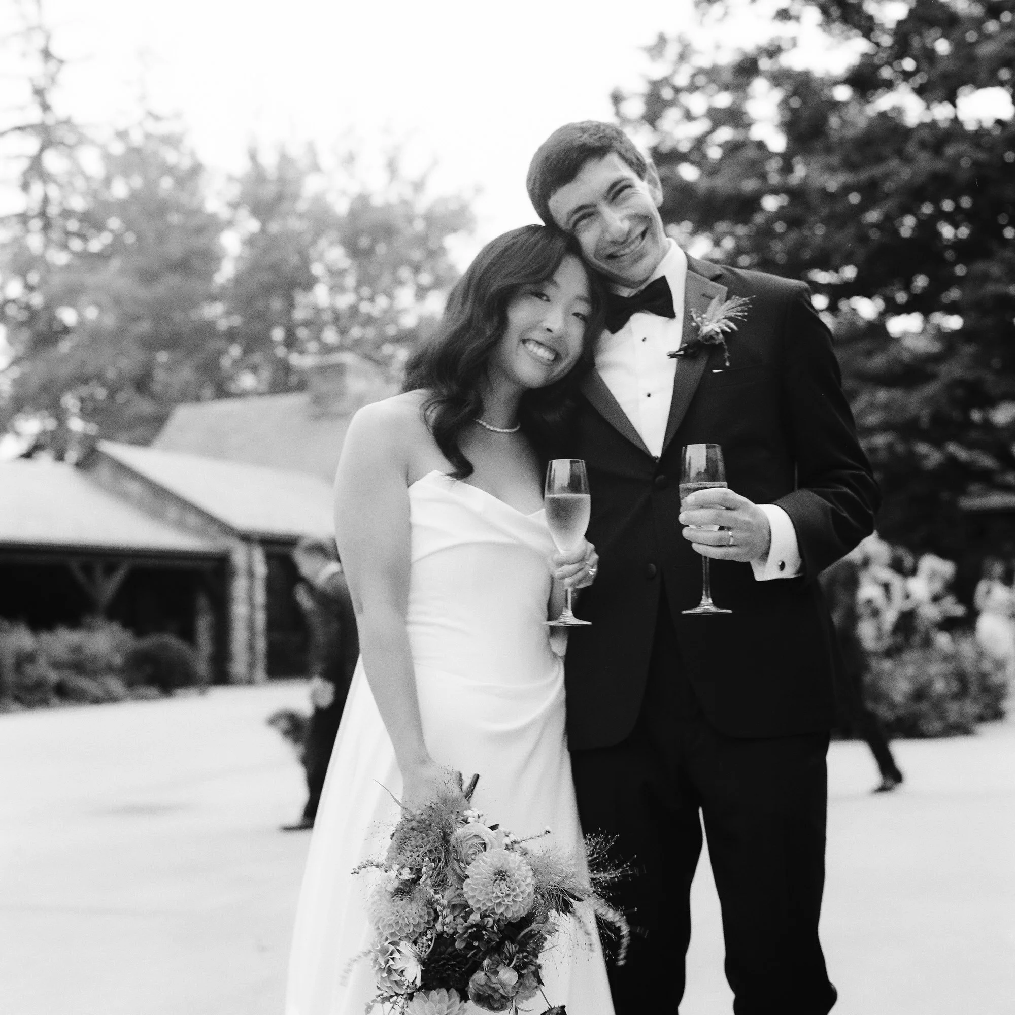 Newlyweds smiling with champagne during cocktail hour in black and white at Blue Hill at Stone Barns, photographed by Jenny Fu.